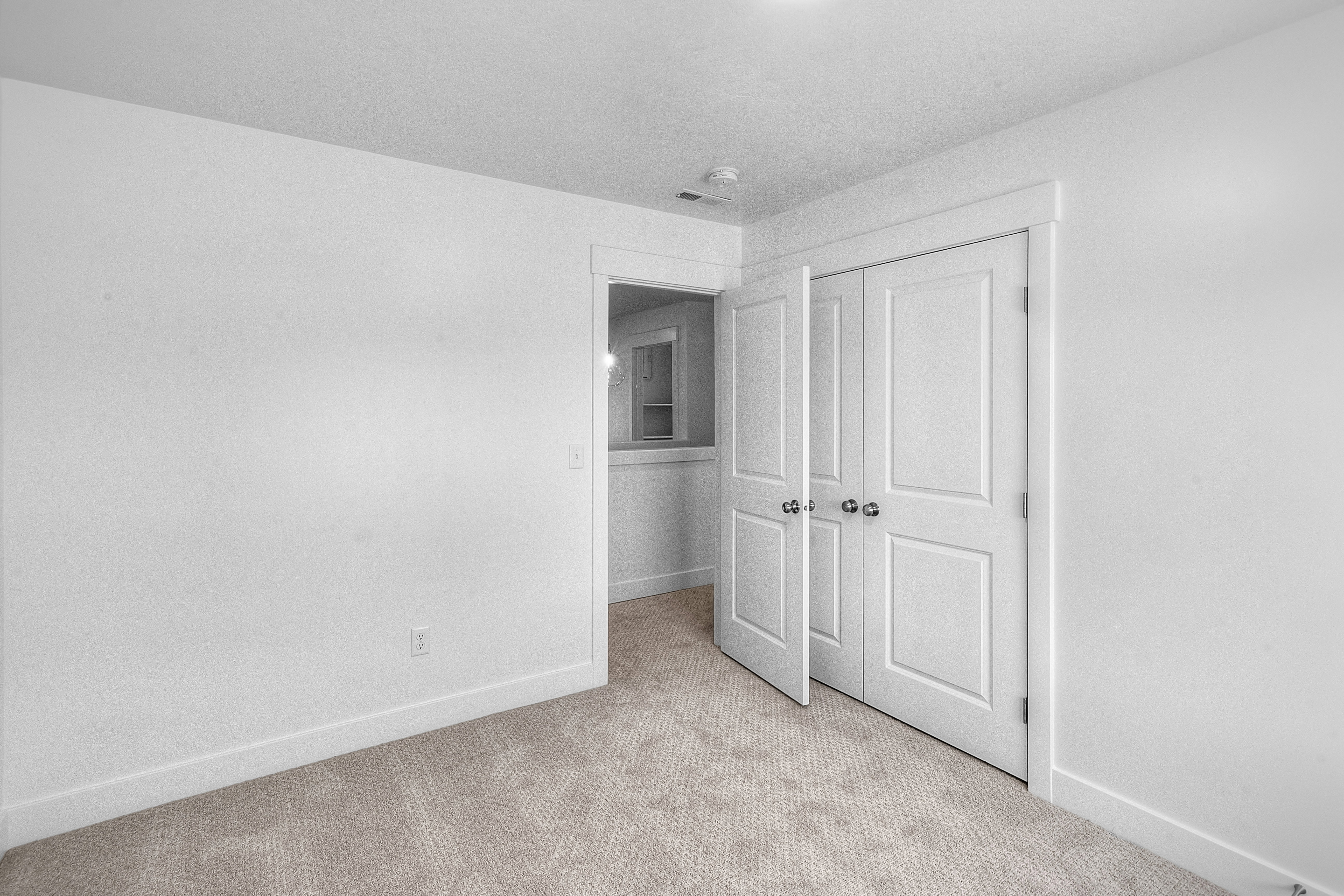 Neutral tone carpet flooring with white baseboards and walls