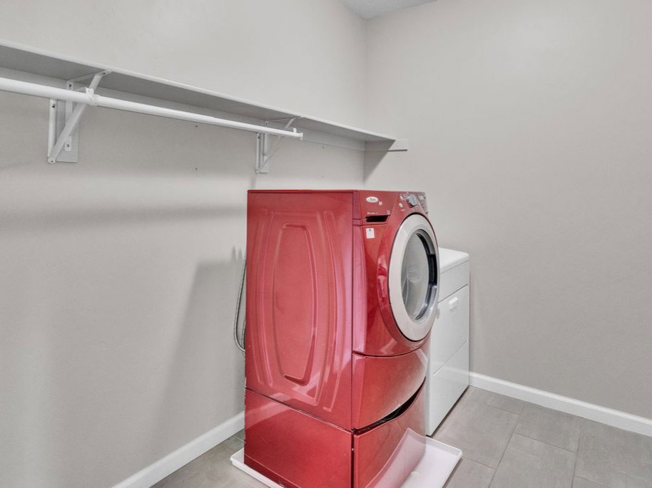 Dedicated utility room featuring gray walls, overhead shelving, and tile flooring