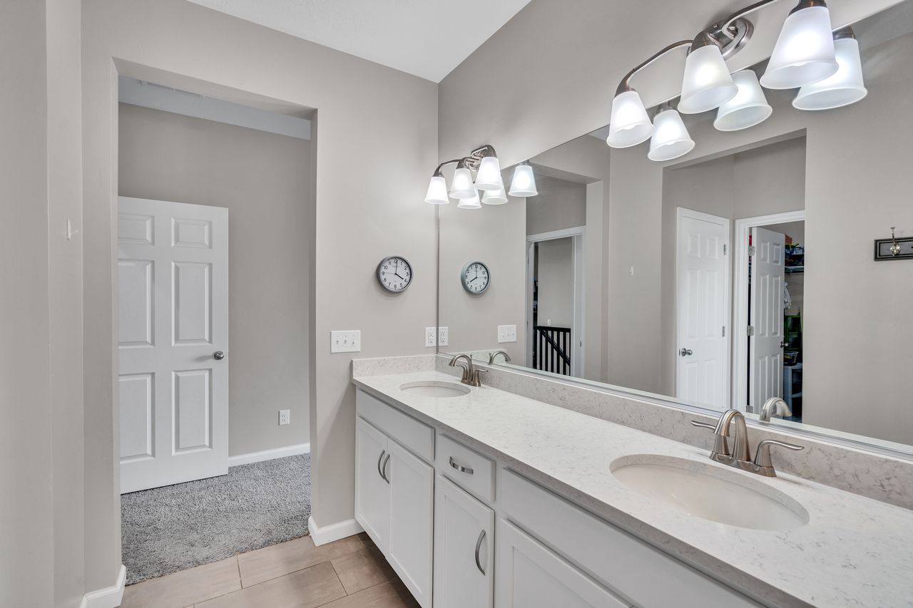 Dual vanity featuring white cabinetry, light-toned countertops, and brushed nickel fixtures
