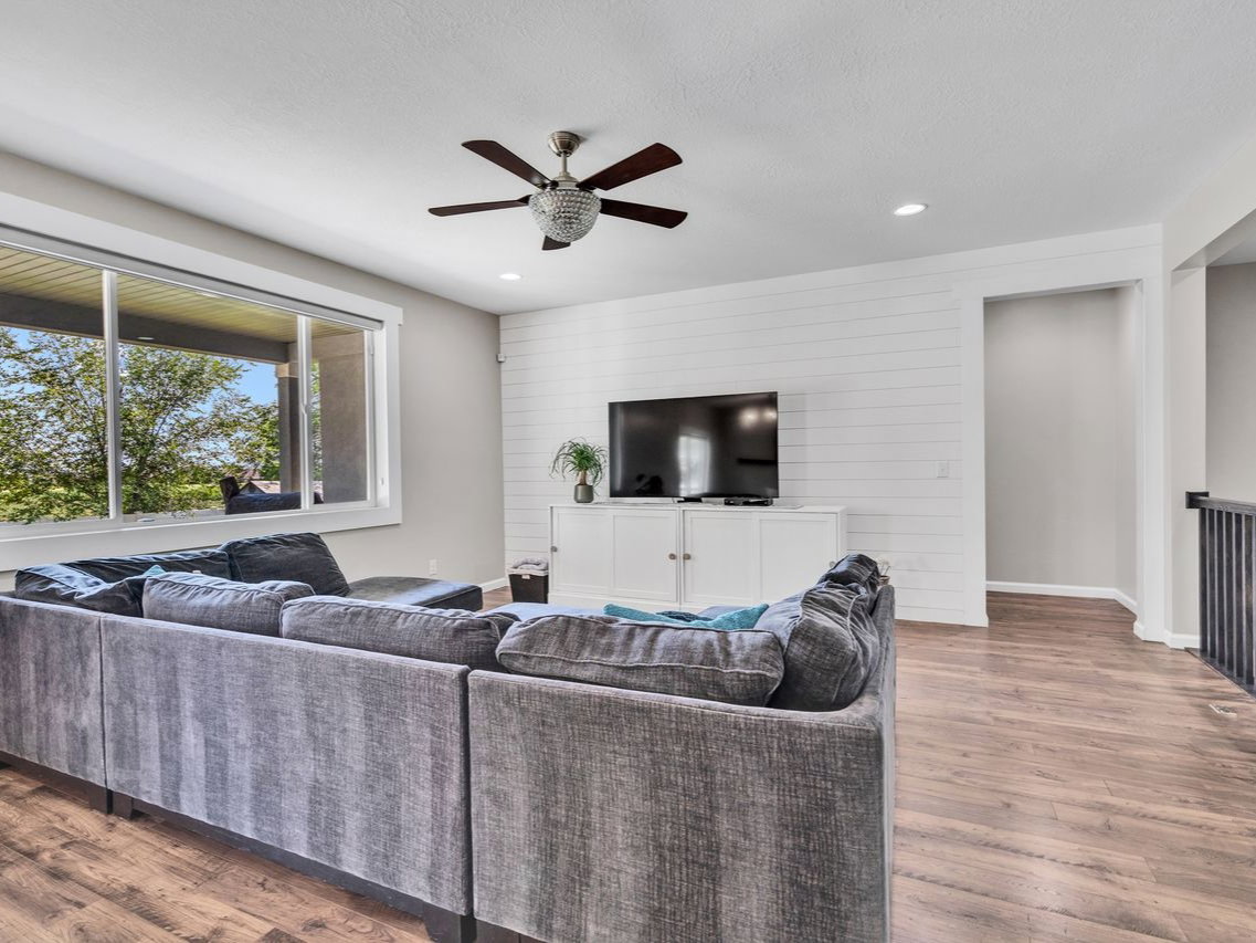 Open-concept living space with wood-finish flooring, a contemporary ceiling fan, recessed lighting, and a shiplap accent wall