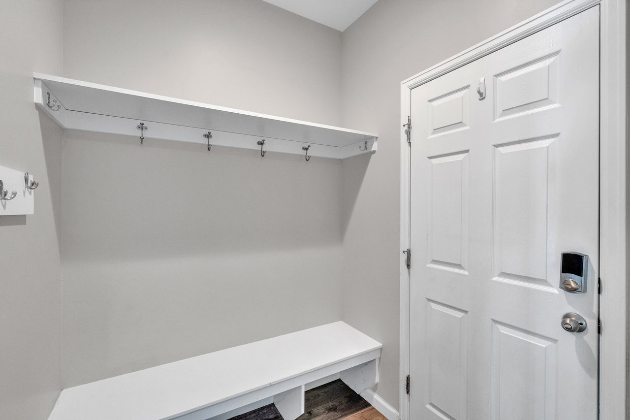 Entryway featuring built-in bench seating, upper shelf storage, and multiple coat hooks