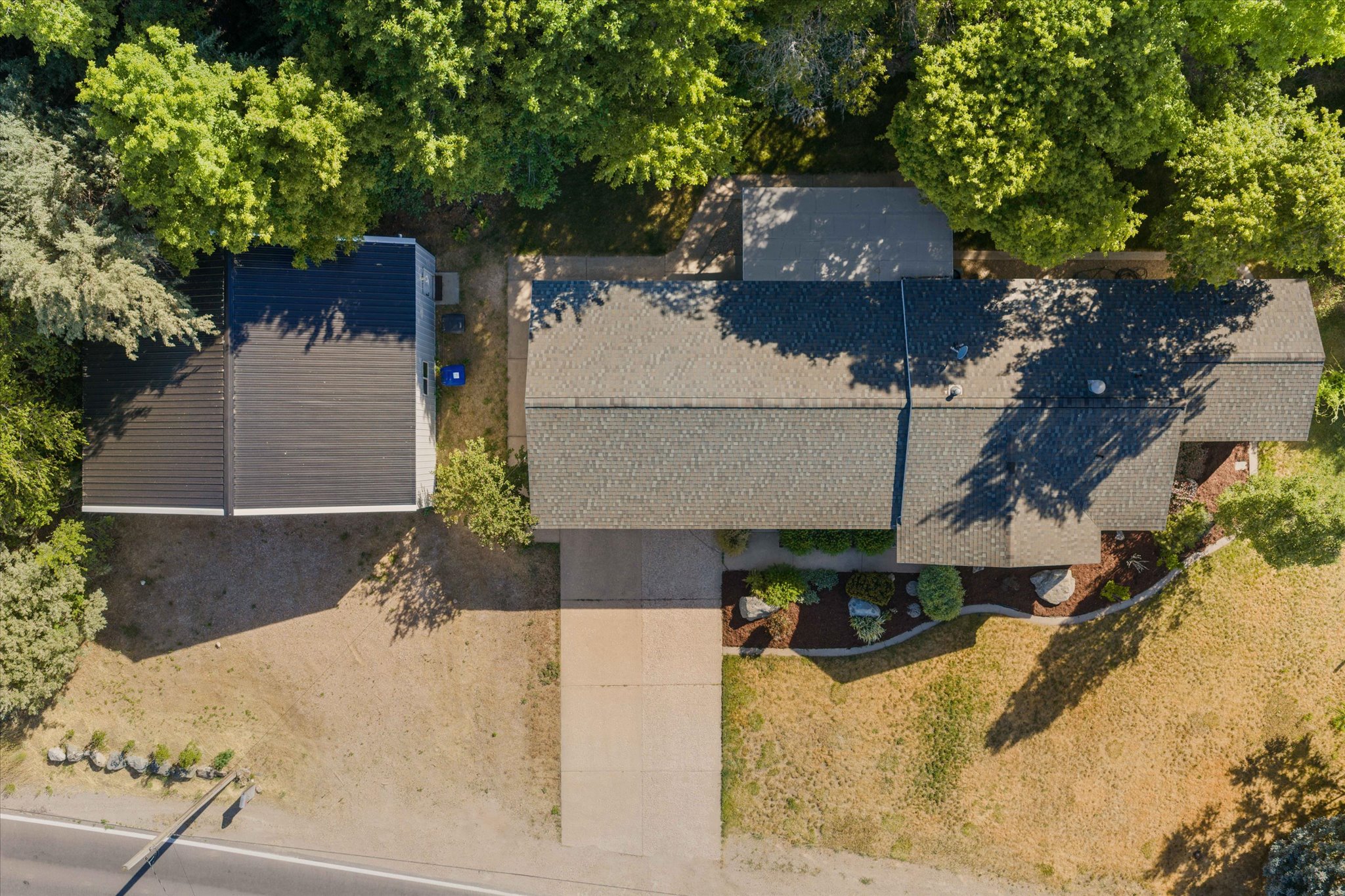 Overhead property view featuring two distinct rooflines, including a dark grey shingle roof and a standing seam metal roof