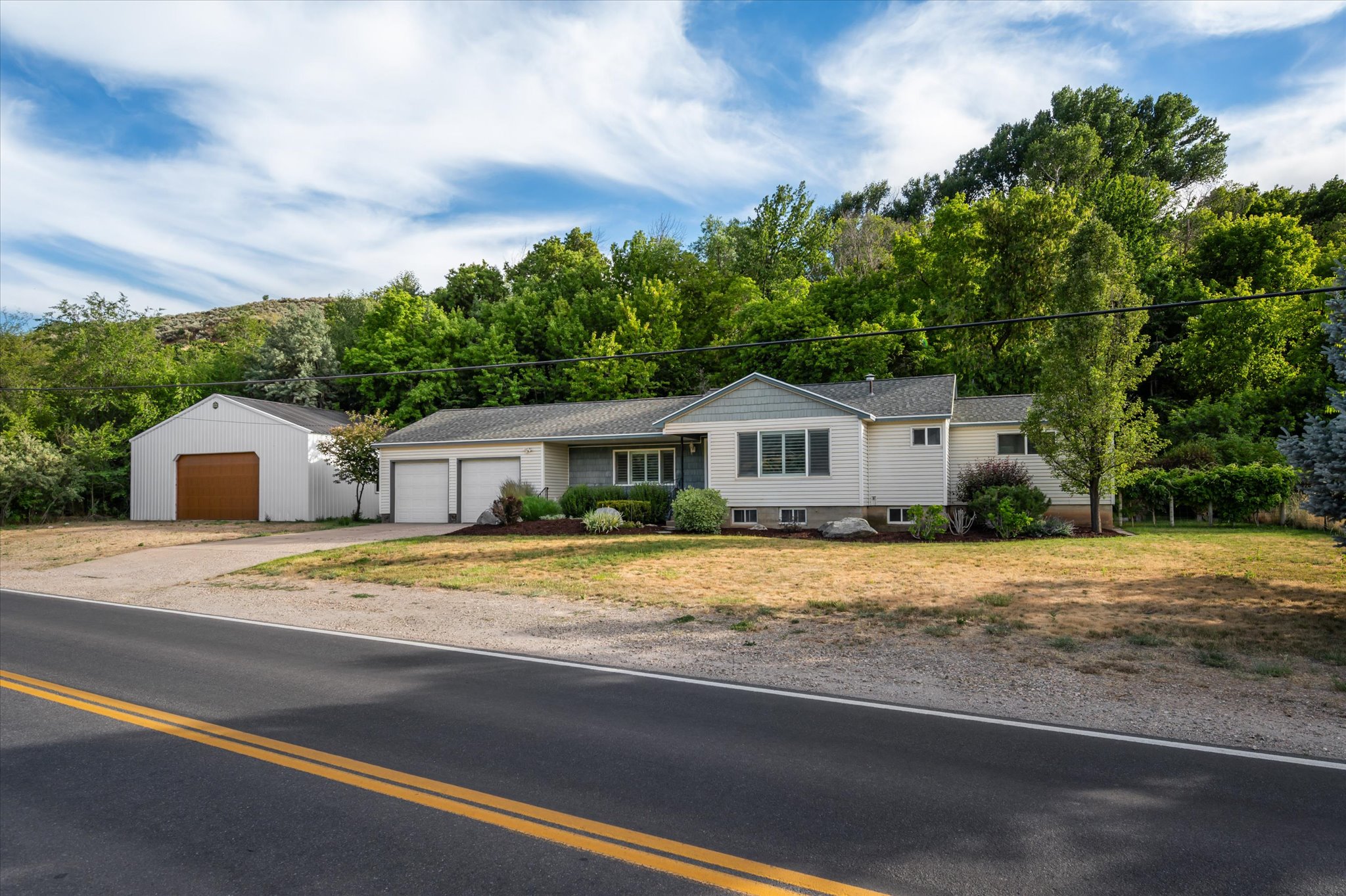 Ranch-style residence featuring a two-car attached garage, additional detached garage, and a sloped shingle roof