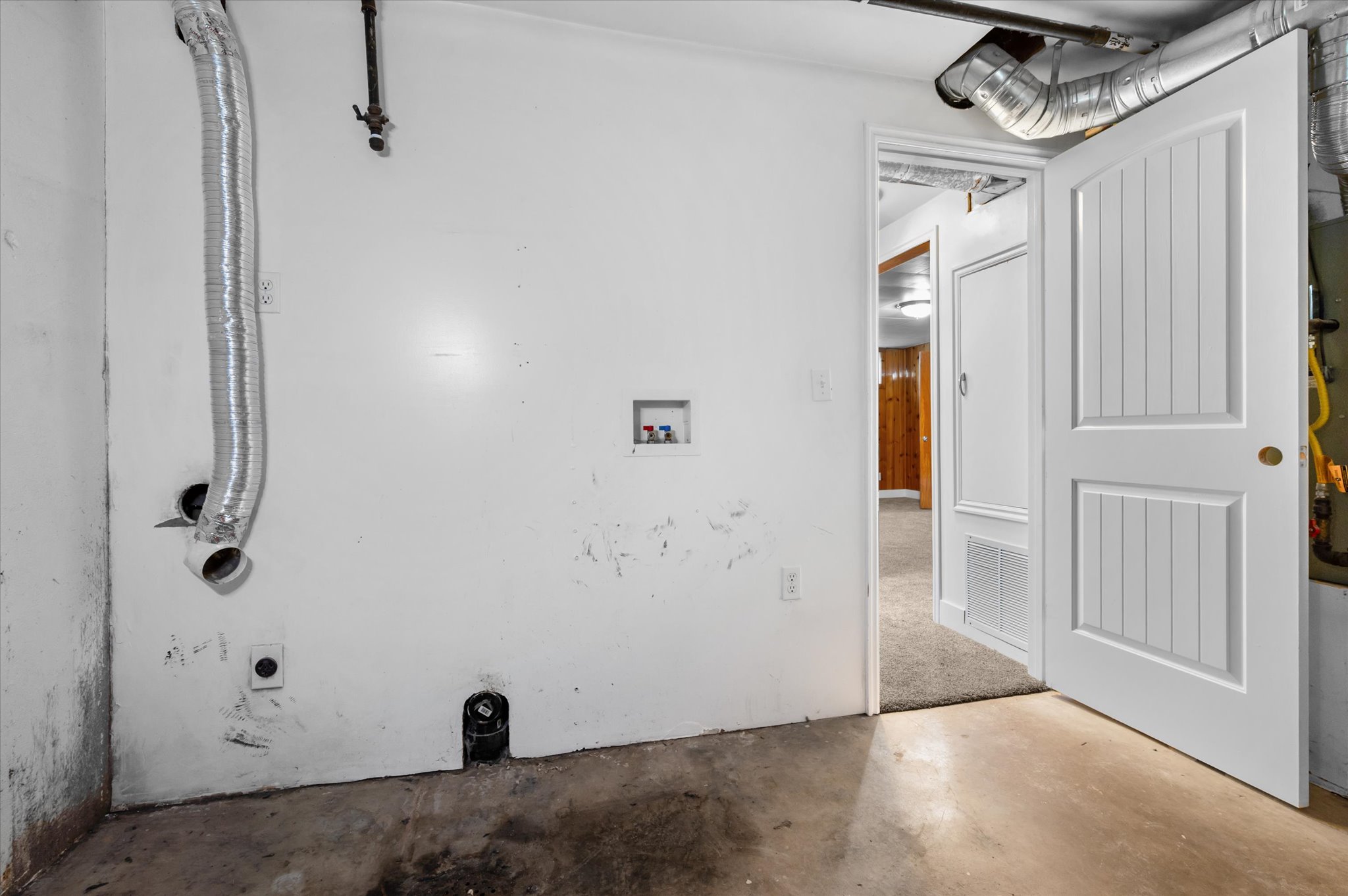 Utility room featuring a washer/dryer hookup, white walls, and concrete flooring