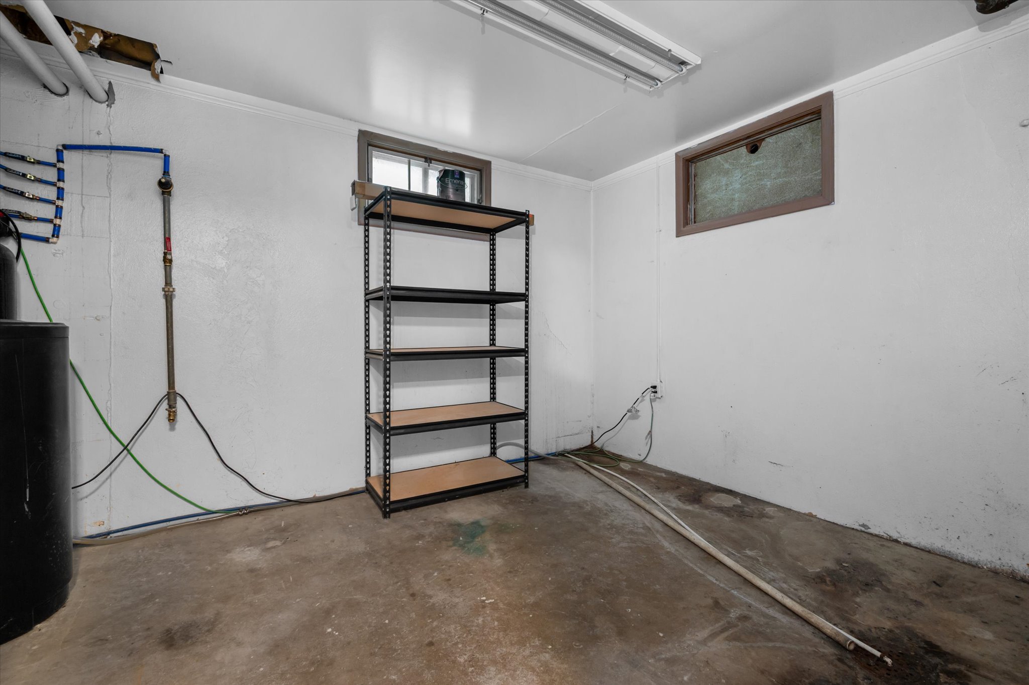 Utility room with concrete flooring, fluorescent overhead lighting, and built-in shelving