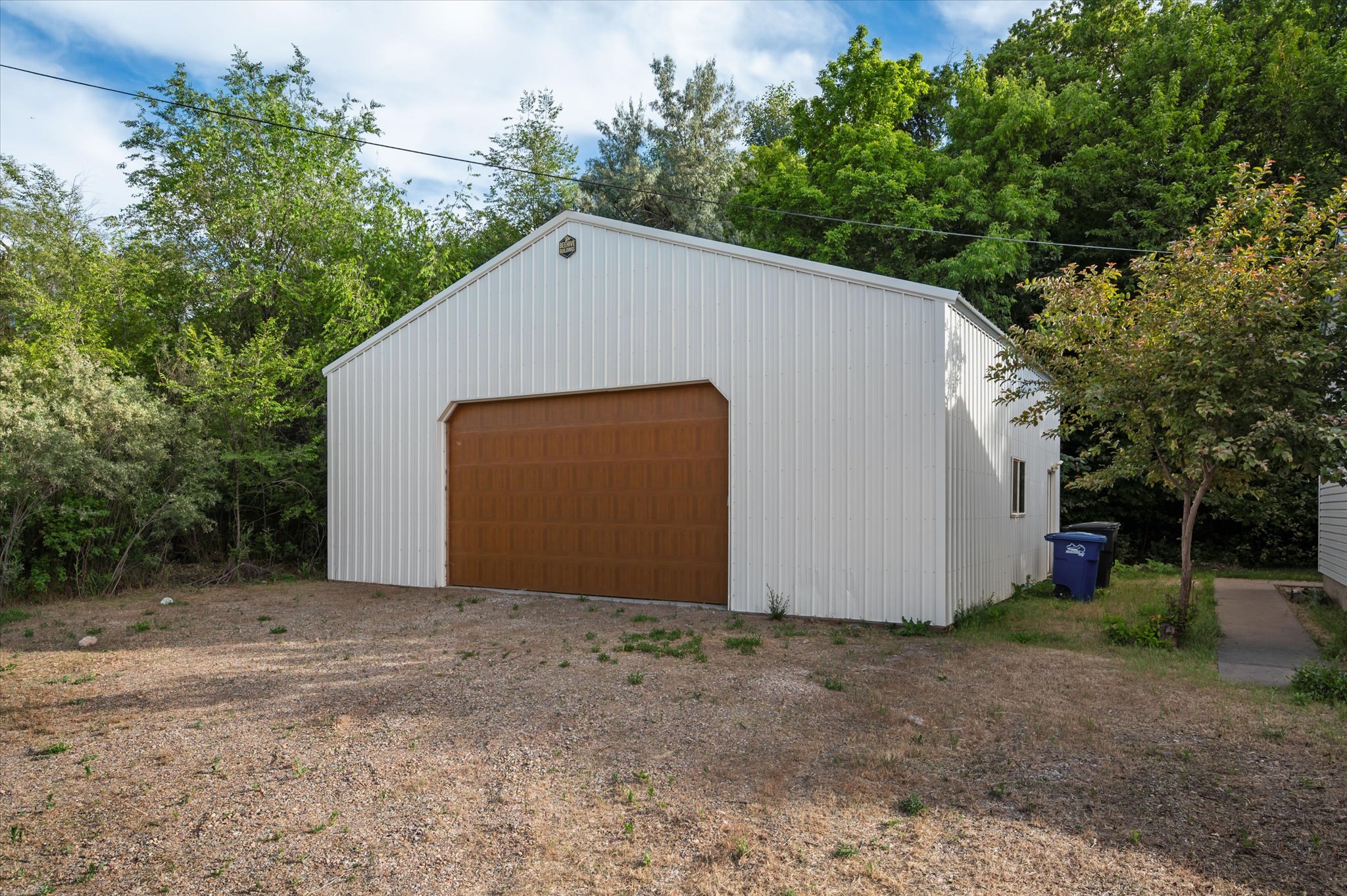 Metal outbuilding featuring a large brown overhead door and a side window
