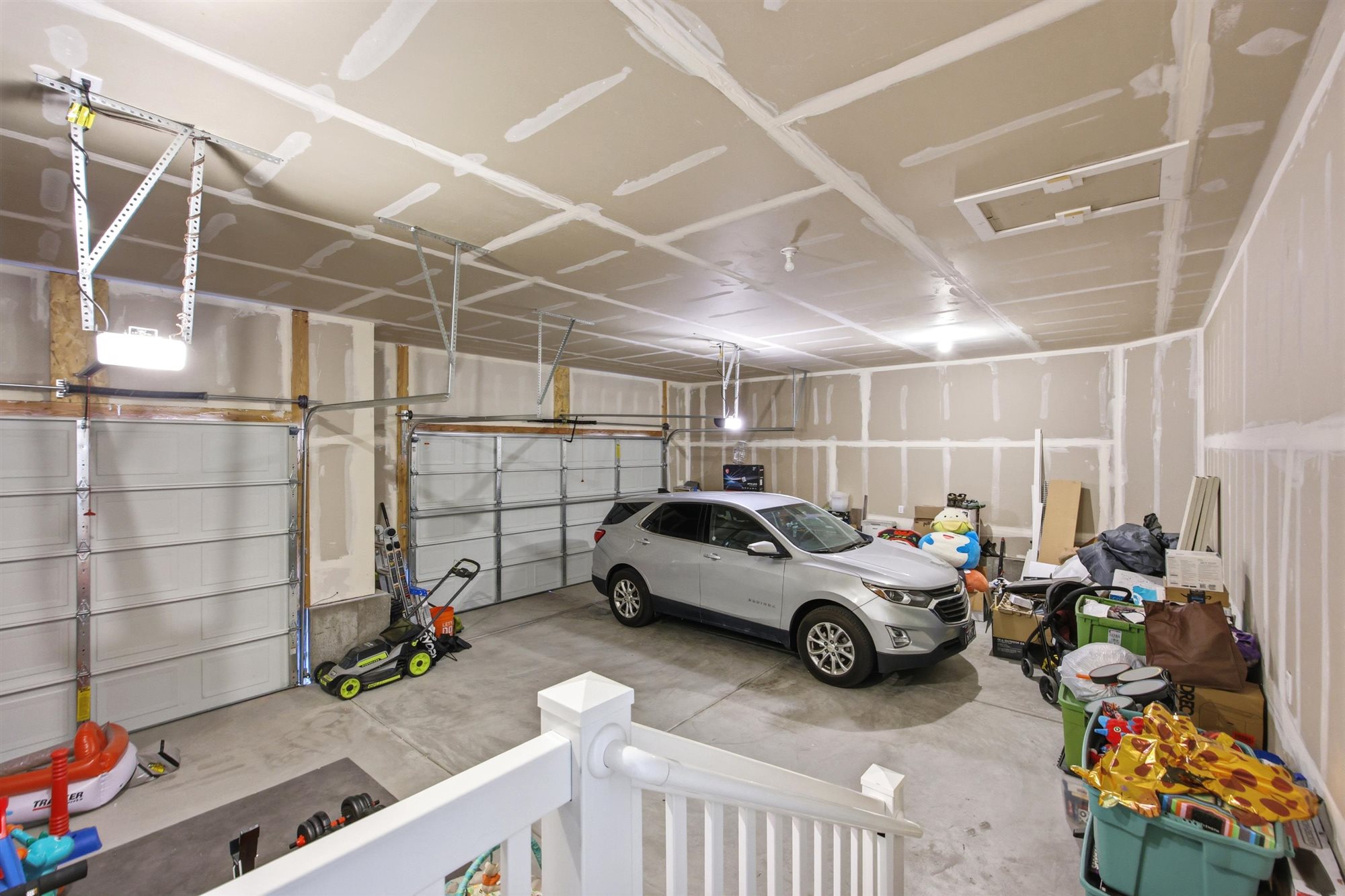 Spacious garage featuring two overhead doors, exposed framing, and a concrete floor