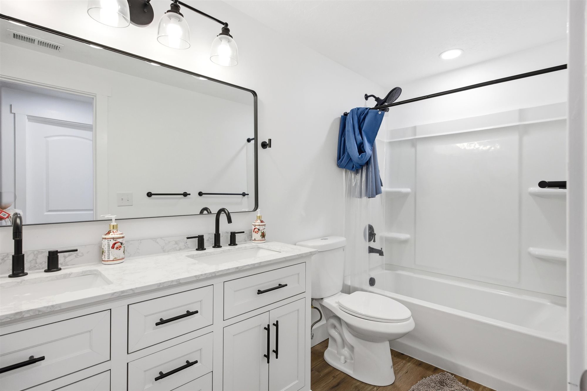 Bathroom featuring a dual vanity with white shaker cabinets, matte black hardware, and light-toned countertops