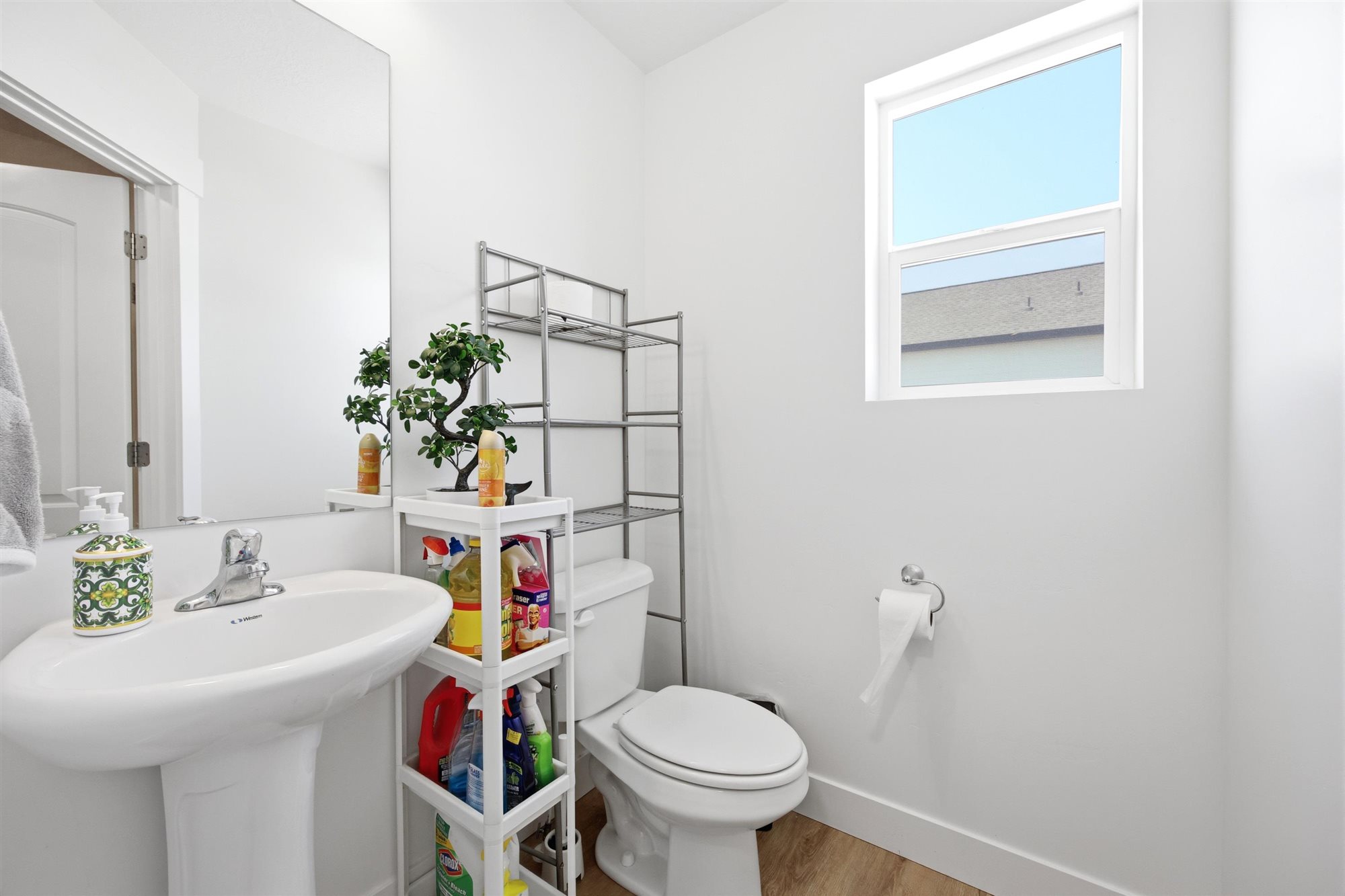 Pedestal sink with chrome faucet, large wall mirror, and white toilet