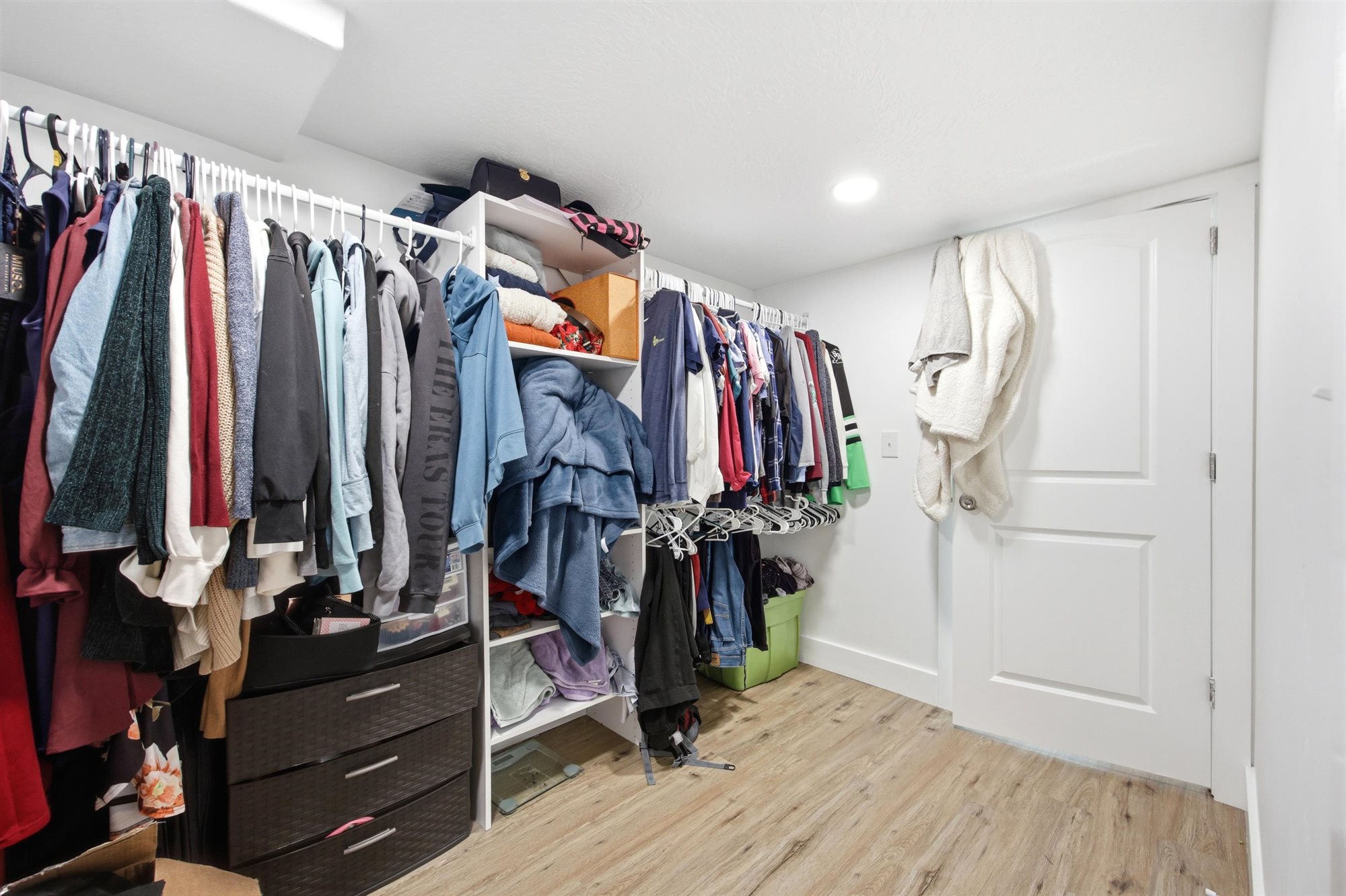 Custom closet system featuring ample hanging space, integrated shelving units, and wood-finish flooring
