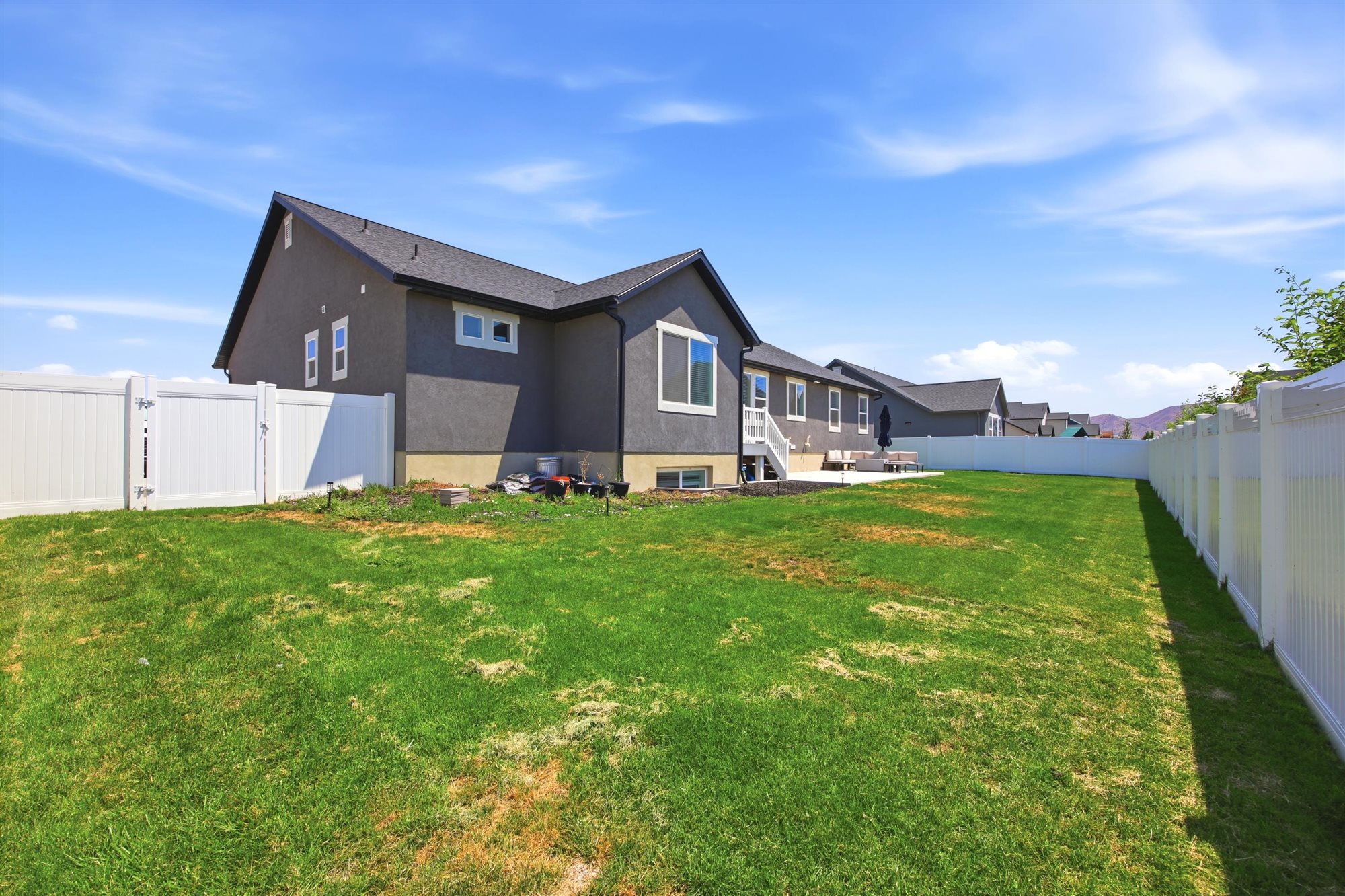 Expansive green lawn surrounds the property, featuring a full privacy fence and a rear patio