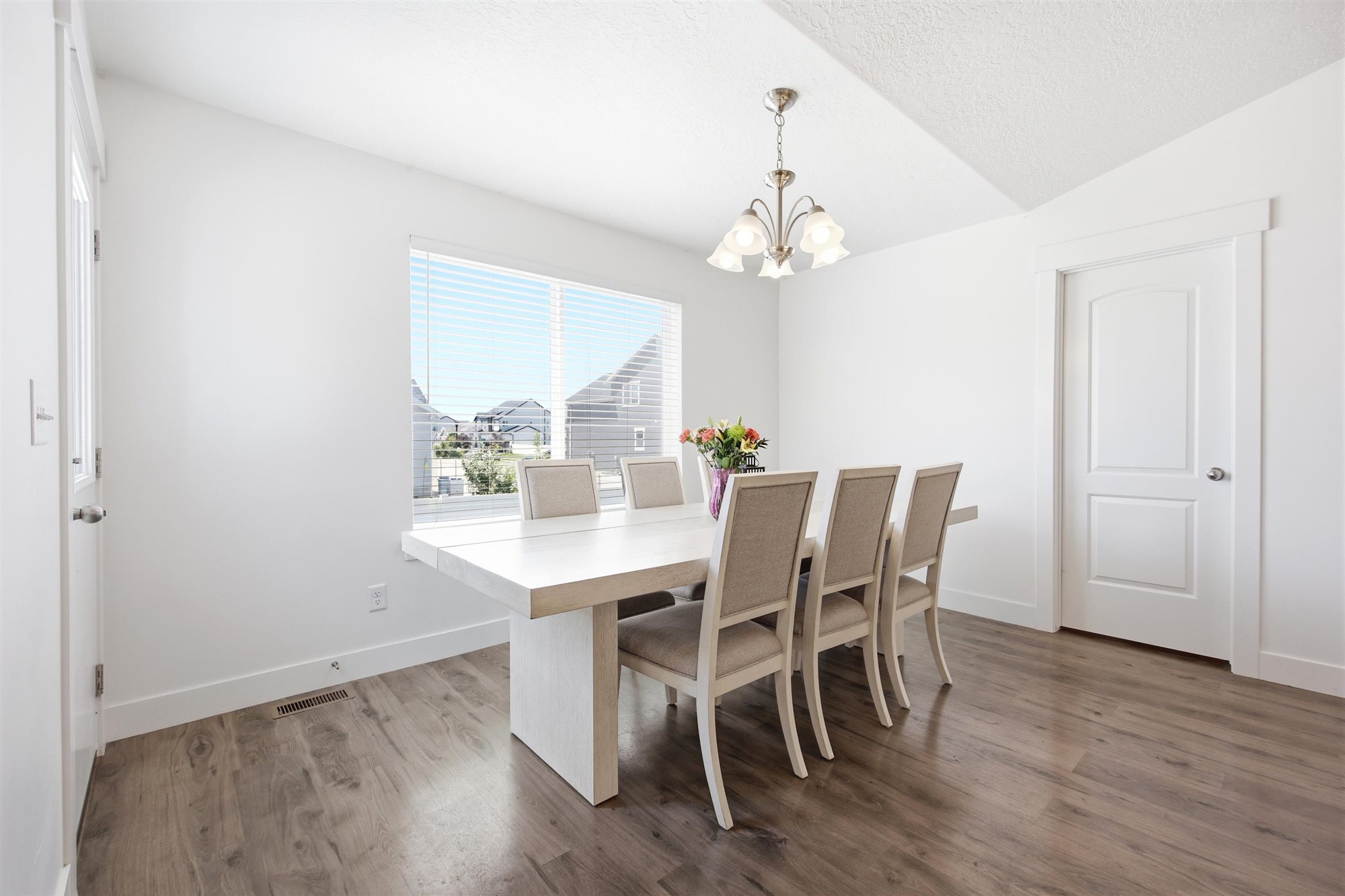 Dining area featuring wood-finish flooring, white walls, and a large window with horizontal blinds