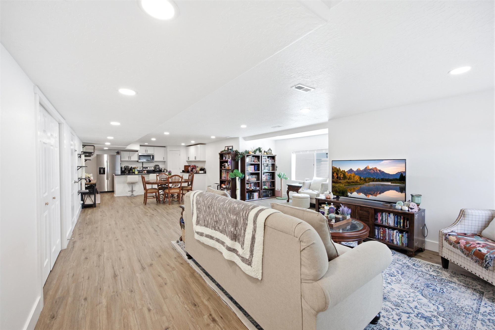 Open-concept living area featuring wood-finish flooring, recessed lighting, and a white color palette