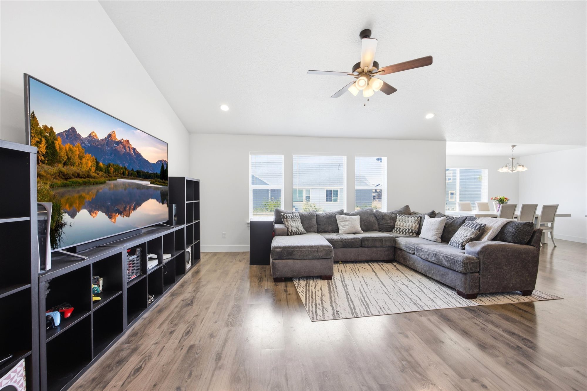 Open-concept living area with wood-finish flooring, a contemporary ceiling fan with light fixture, and recessed lighting