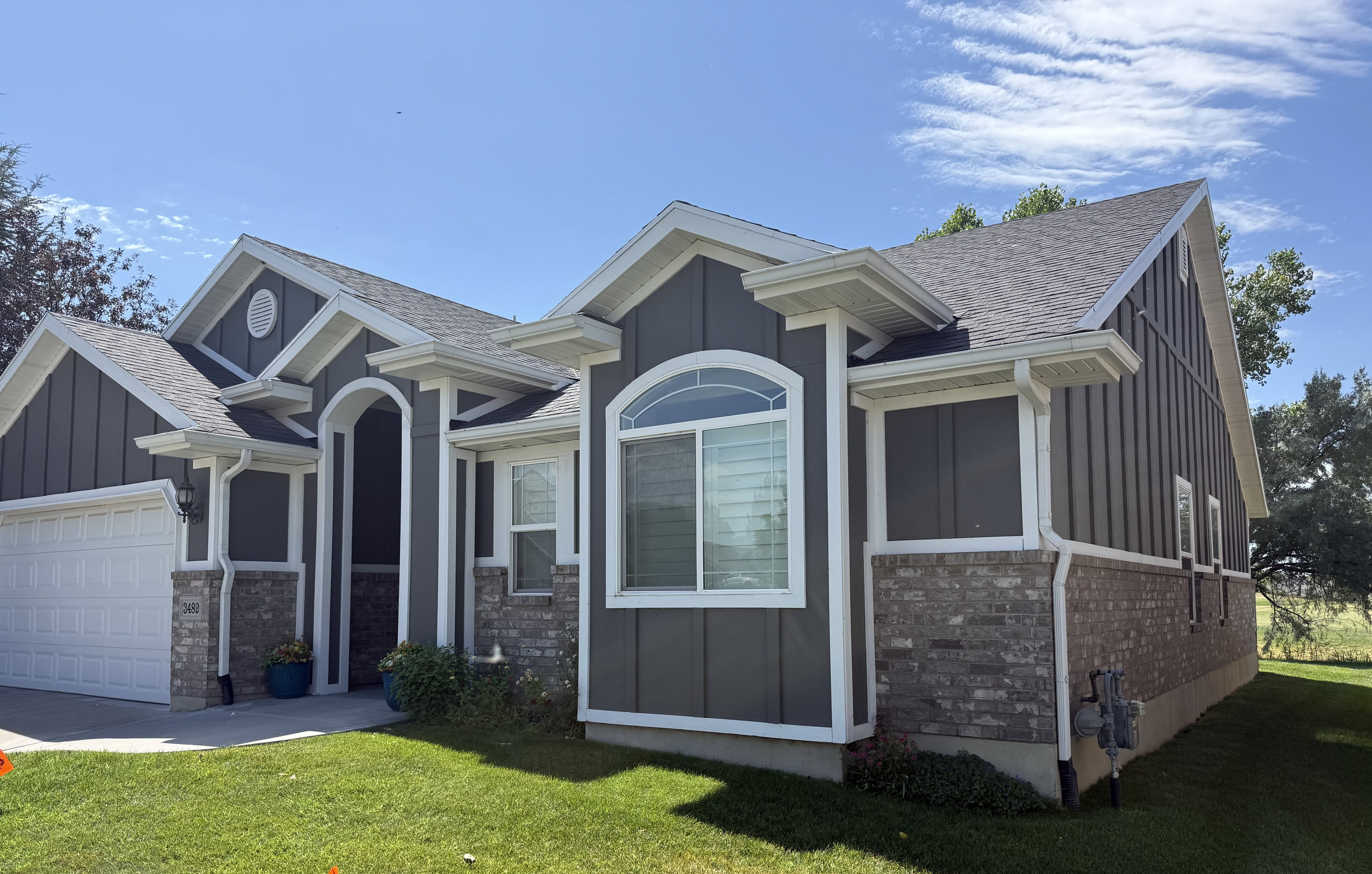 Modern residence featuring a gray vertical siding and brick veneer exterior