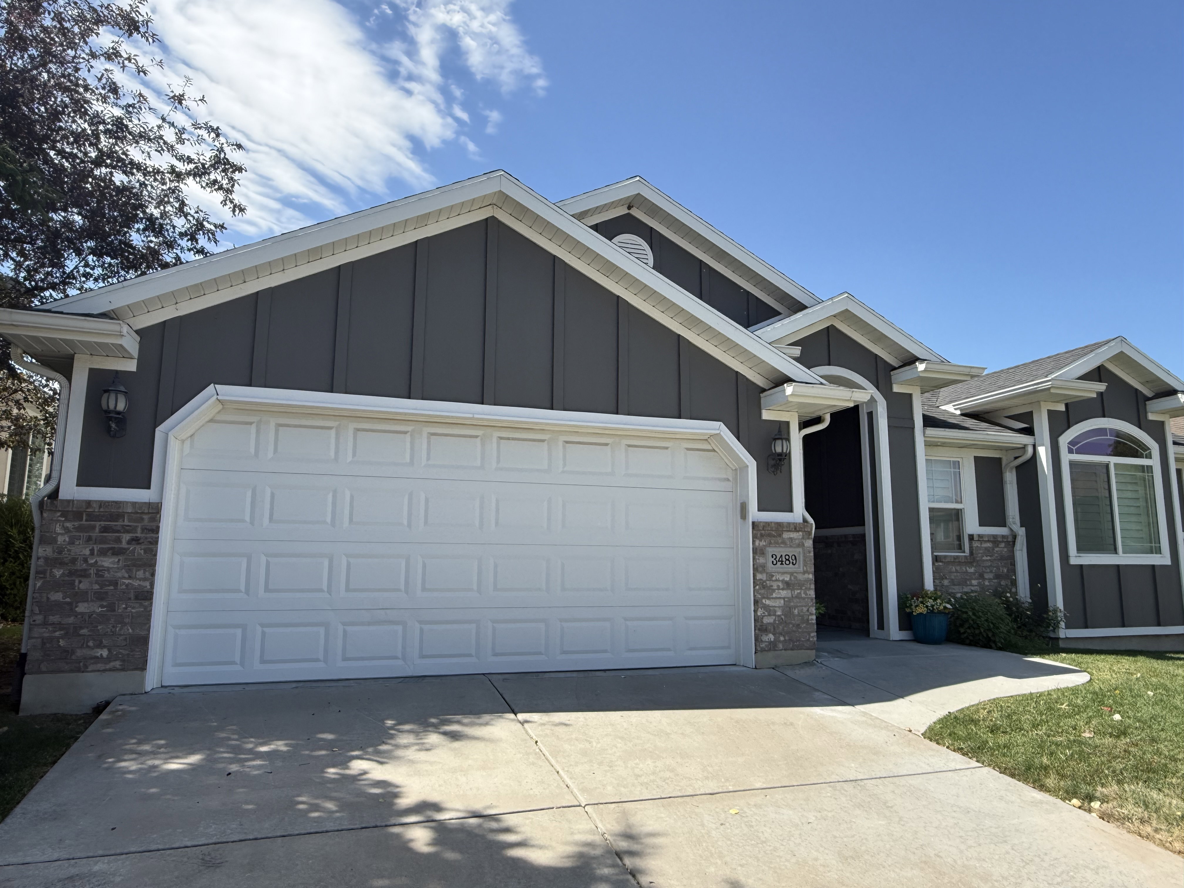 Exterior featuring dark vertical siding accents, white trim, and a white paneled garage door