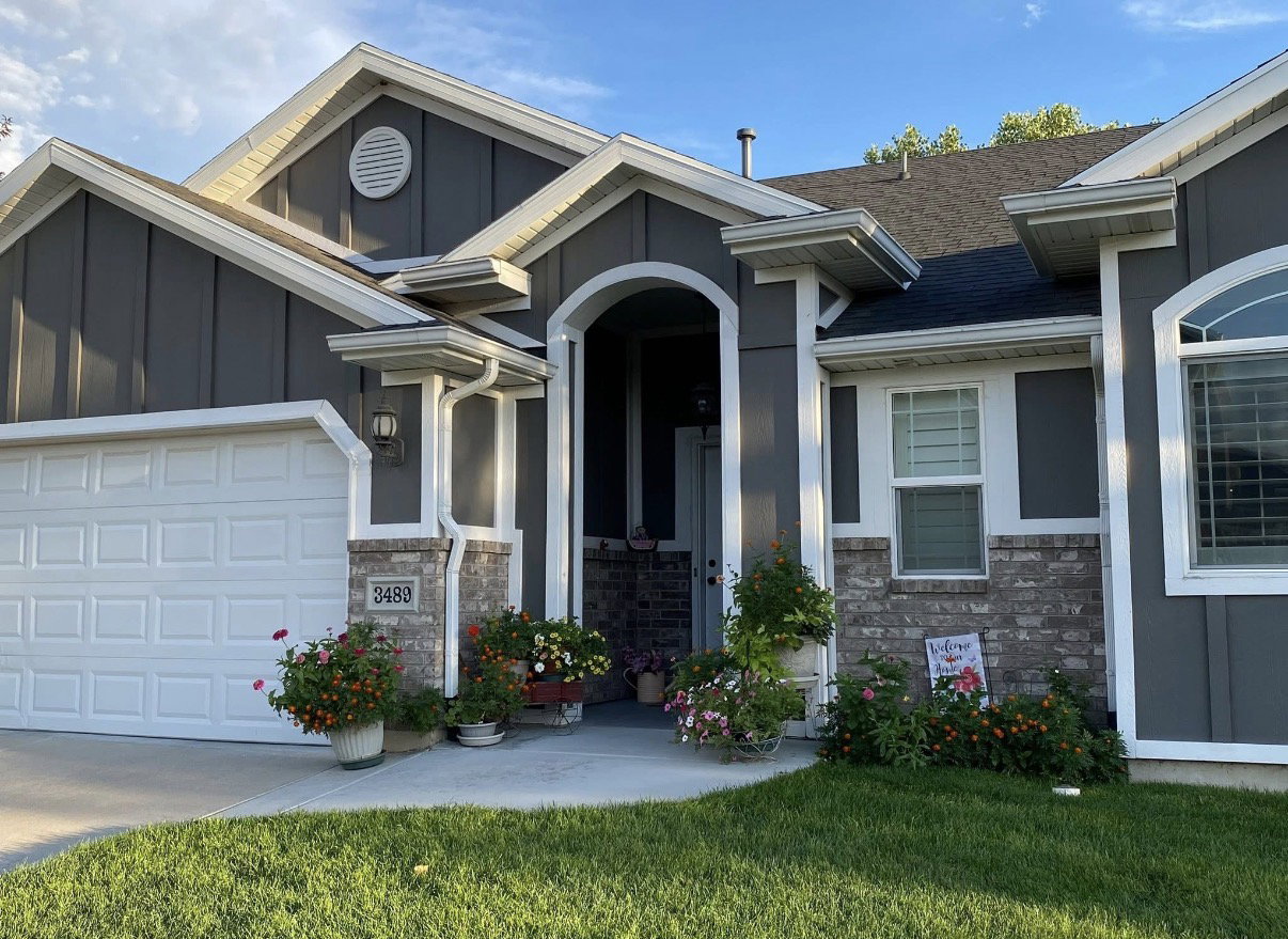 Darling Cottage -style residence featuring grey siding with white trim and a contrasting dark roof