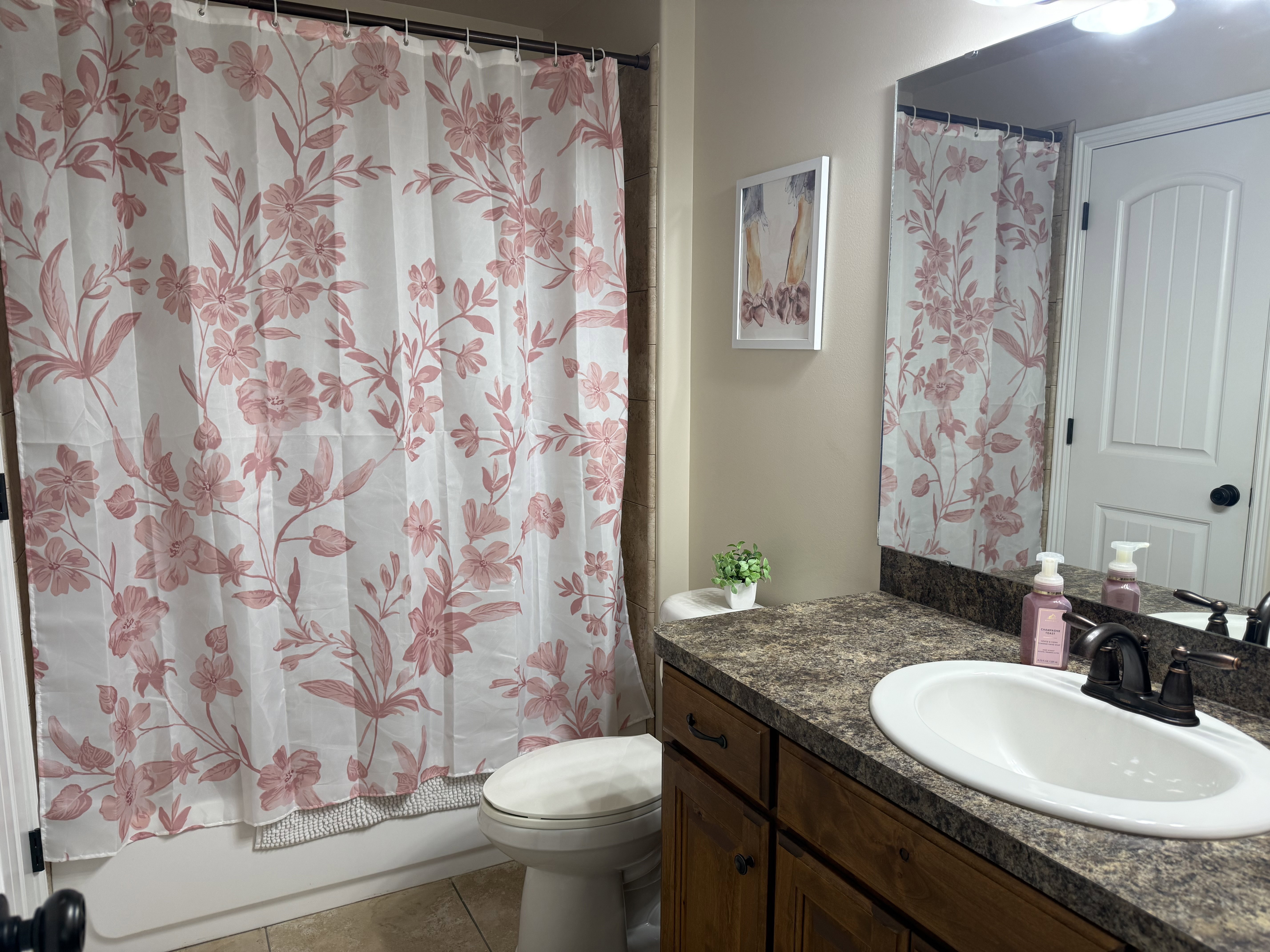 Bathroom featuring a bathtub with tile surround, a built-in vanity with countertop, an integrated sink, and an oil-rubbed bronze faucet