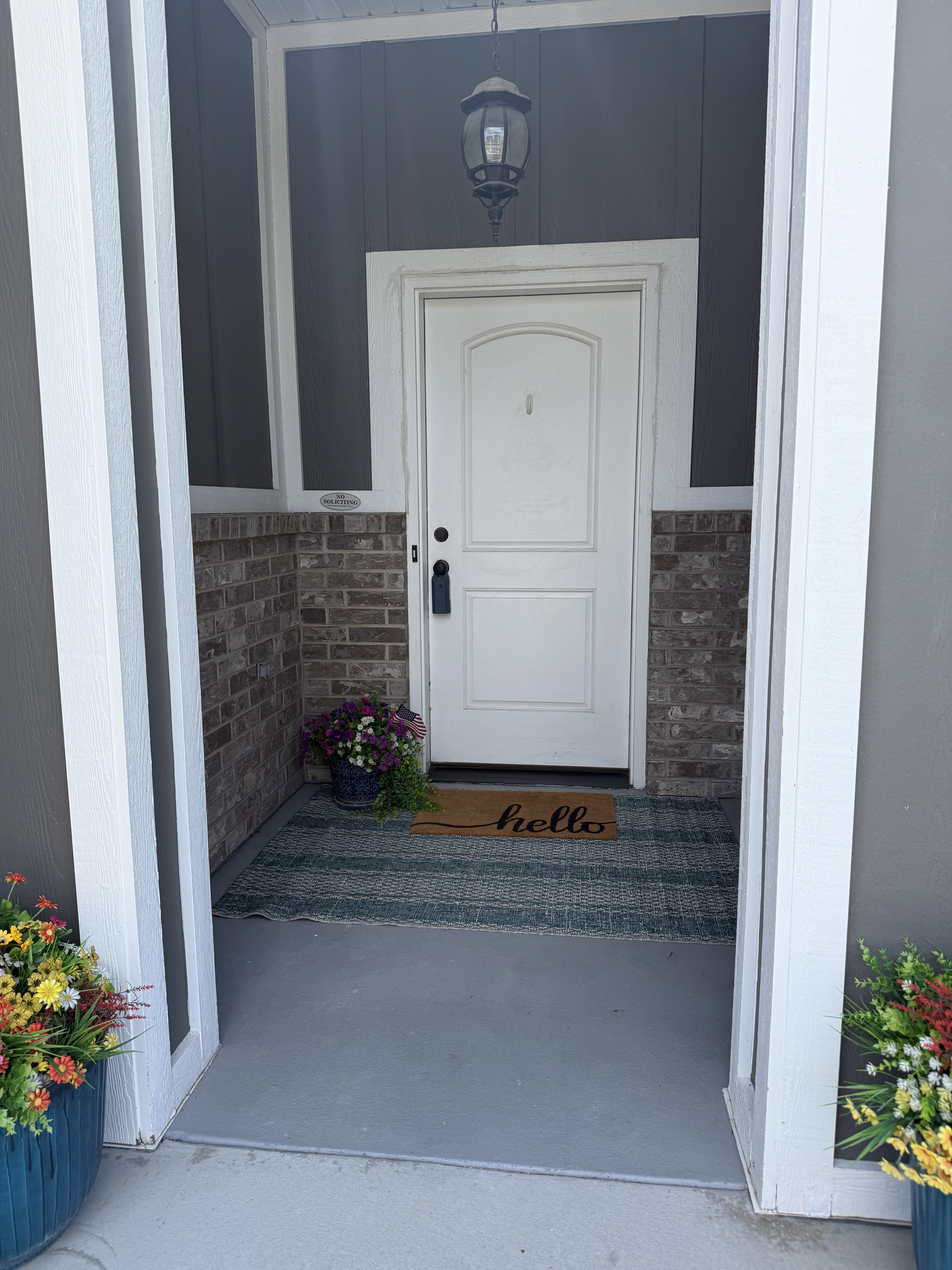 Front entry with white paneled door, black hardware, and an overhead pendant light fixture