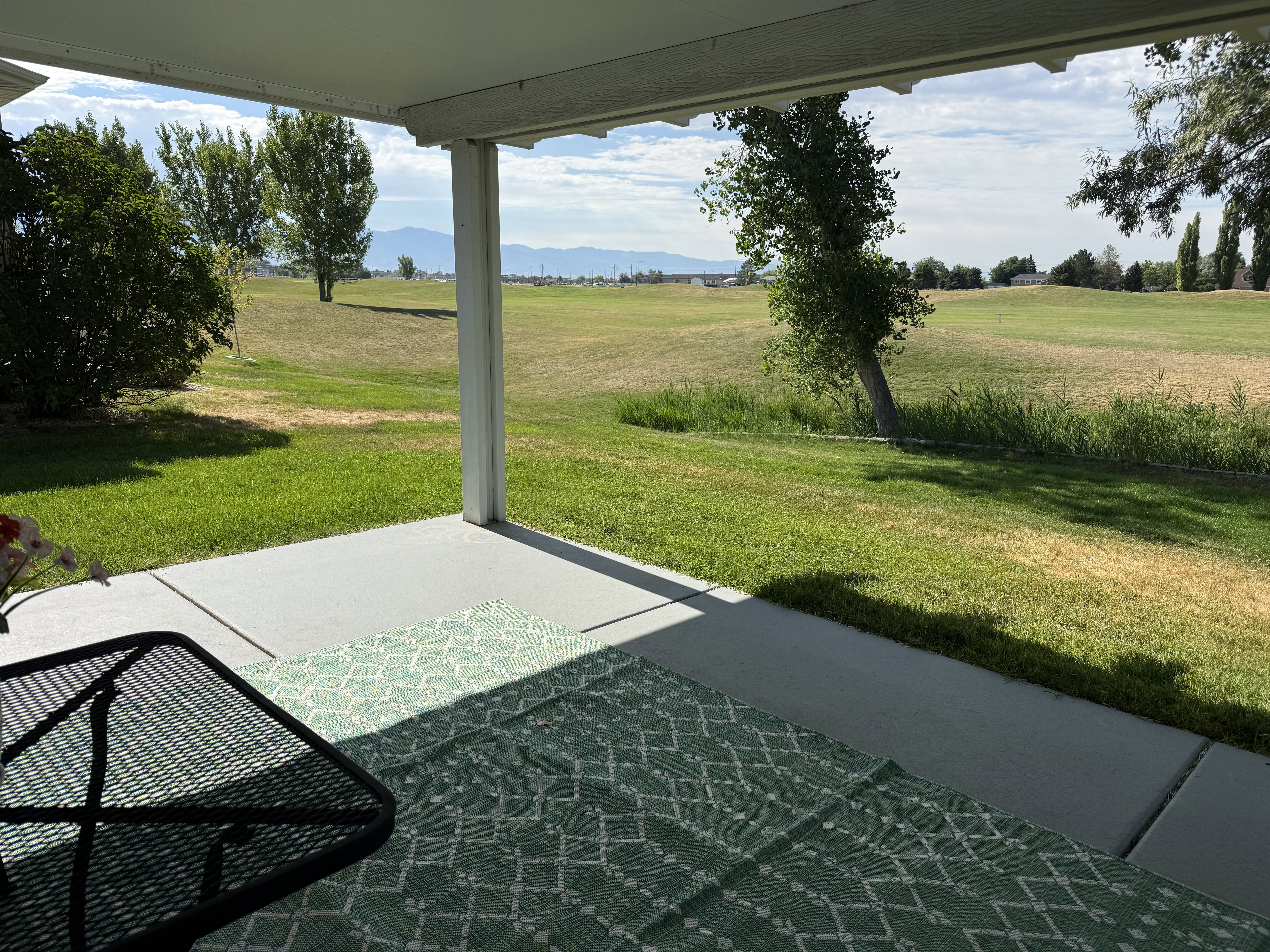 Covered concrete patio overlooking Glen Eagle Golf Course with distant mountain scenery