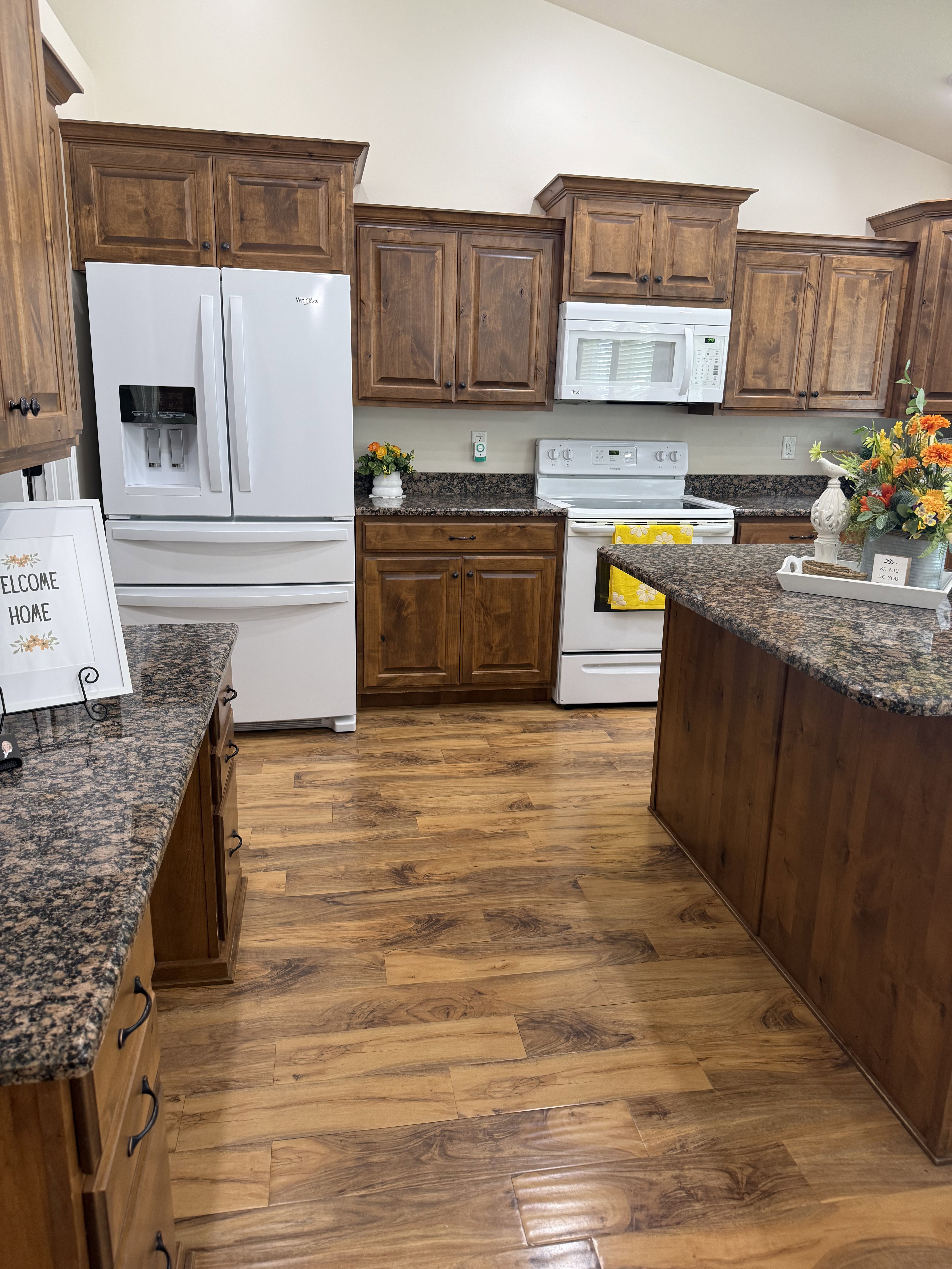 Kitchen featuring wood-finish flooring, dark granite countertops, and wood cabinetry