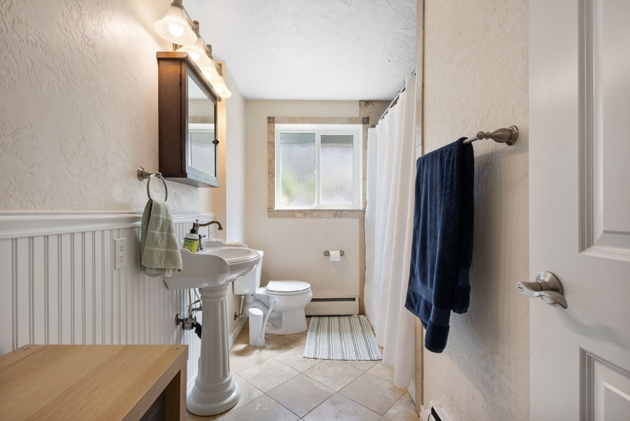 Bathroom with a pedestal sink, wall-mounted medicine cabinet, and tiled flooring