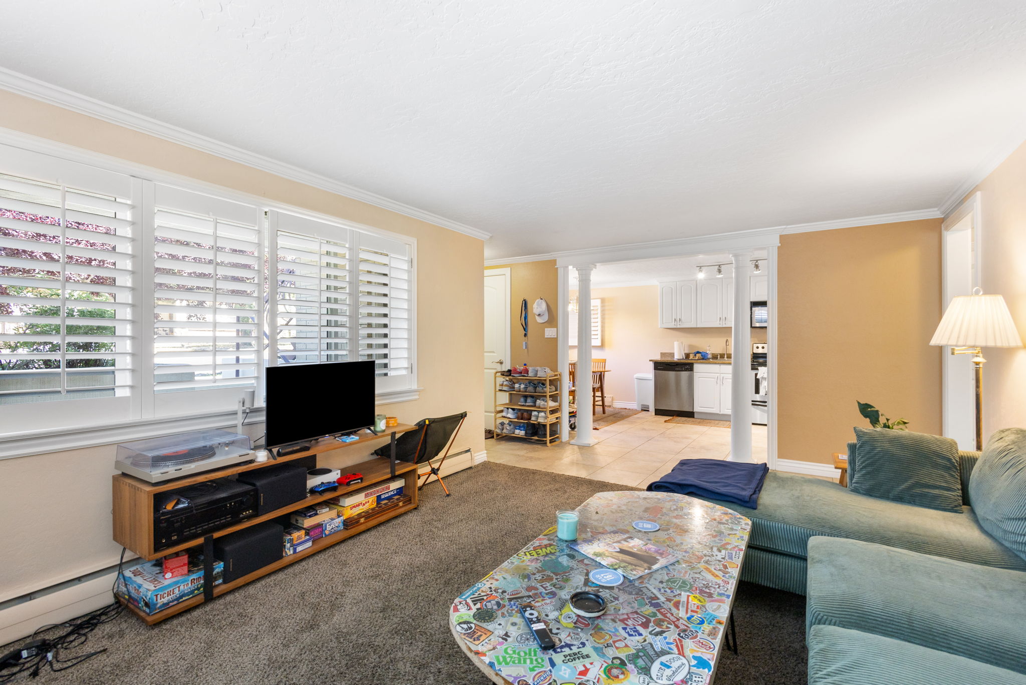 Living area featuring plantation shutters, neutral wall tones, and carpet flooring