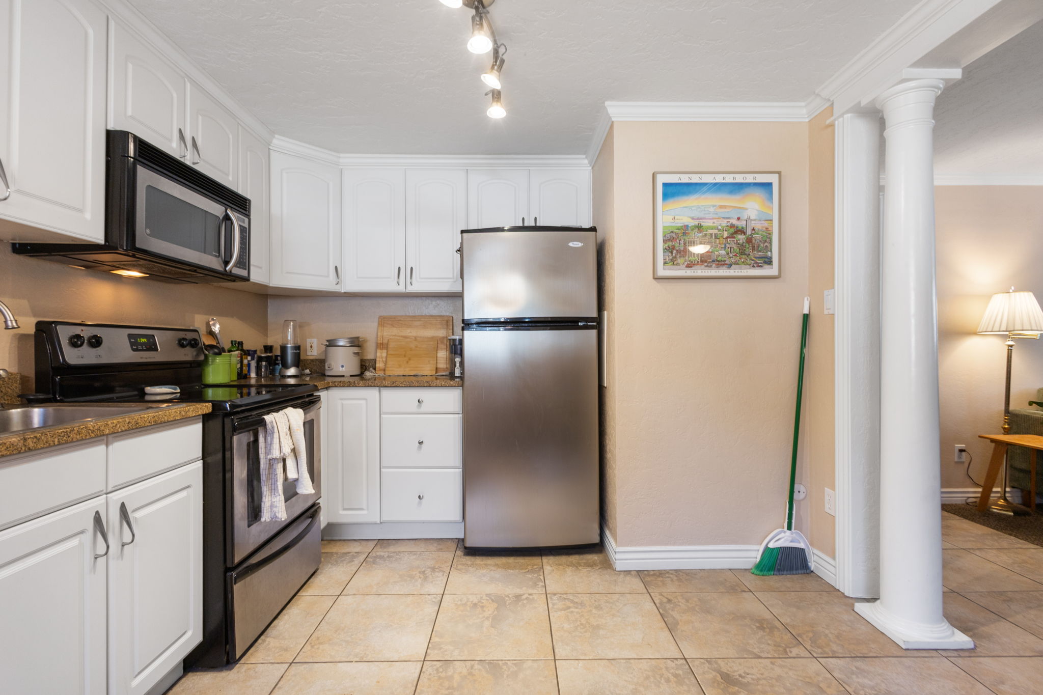 Kitchen featuring white cabinetry with silver hardware, stone countertops, and tile flooring