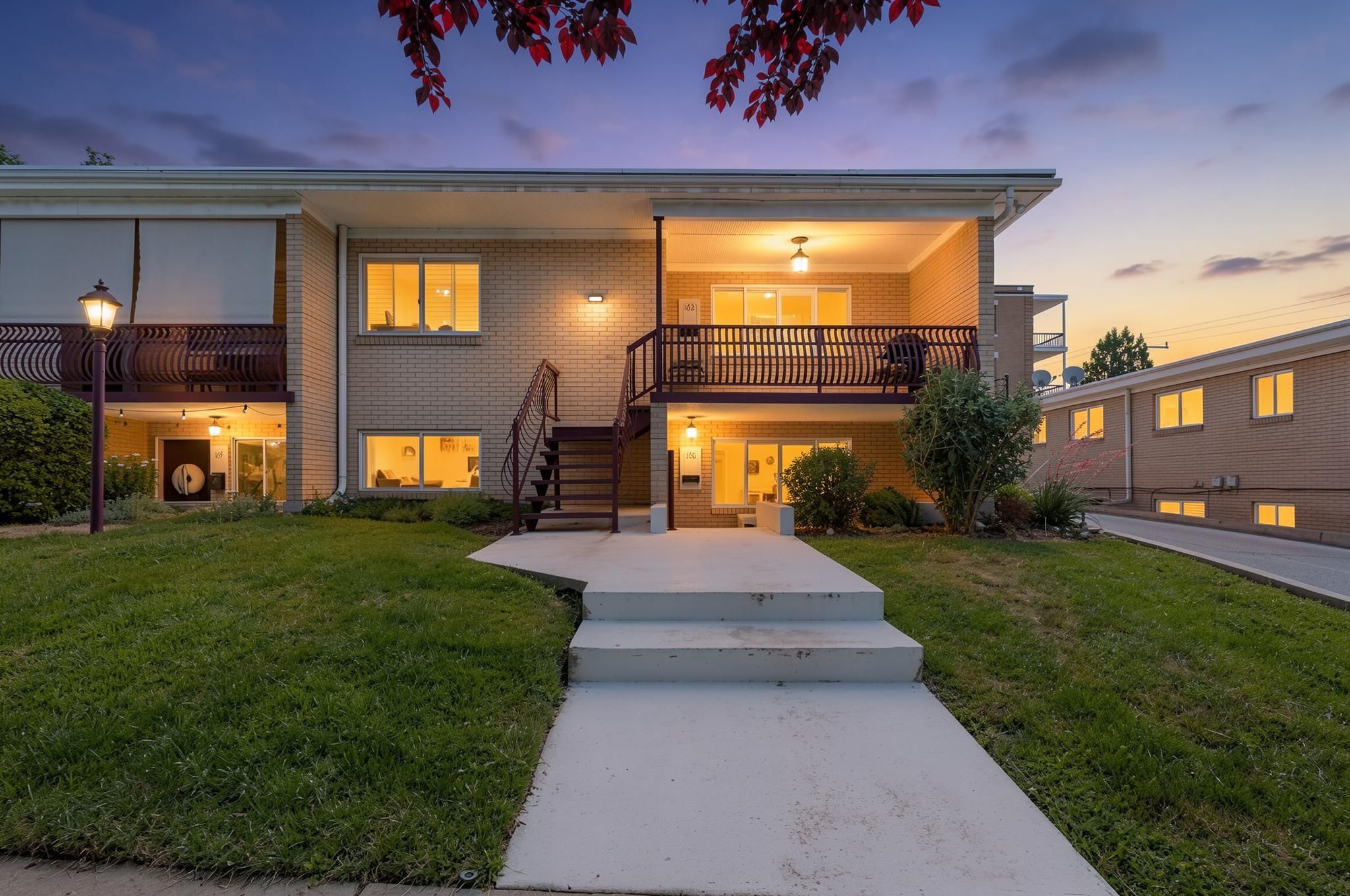 Brick facade building featuring multiple levels, a front lawn, and concrete walkways