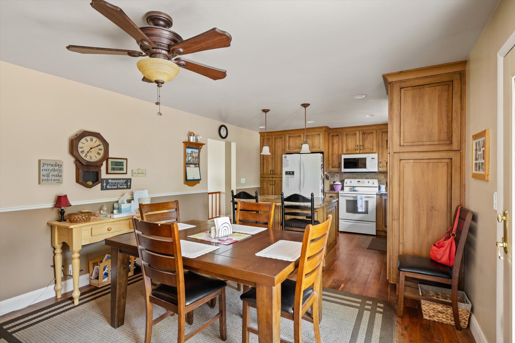 Open-concept dining area featuring wood-finish flooring, a ceiling fan with integrated lighting, and a two-tone wall treatment