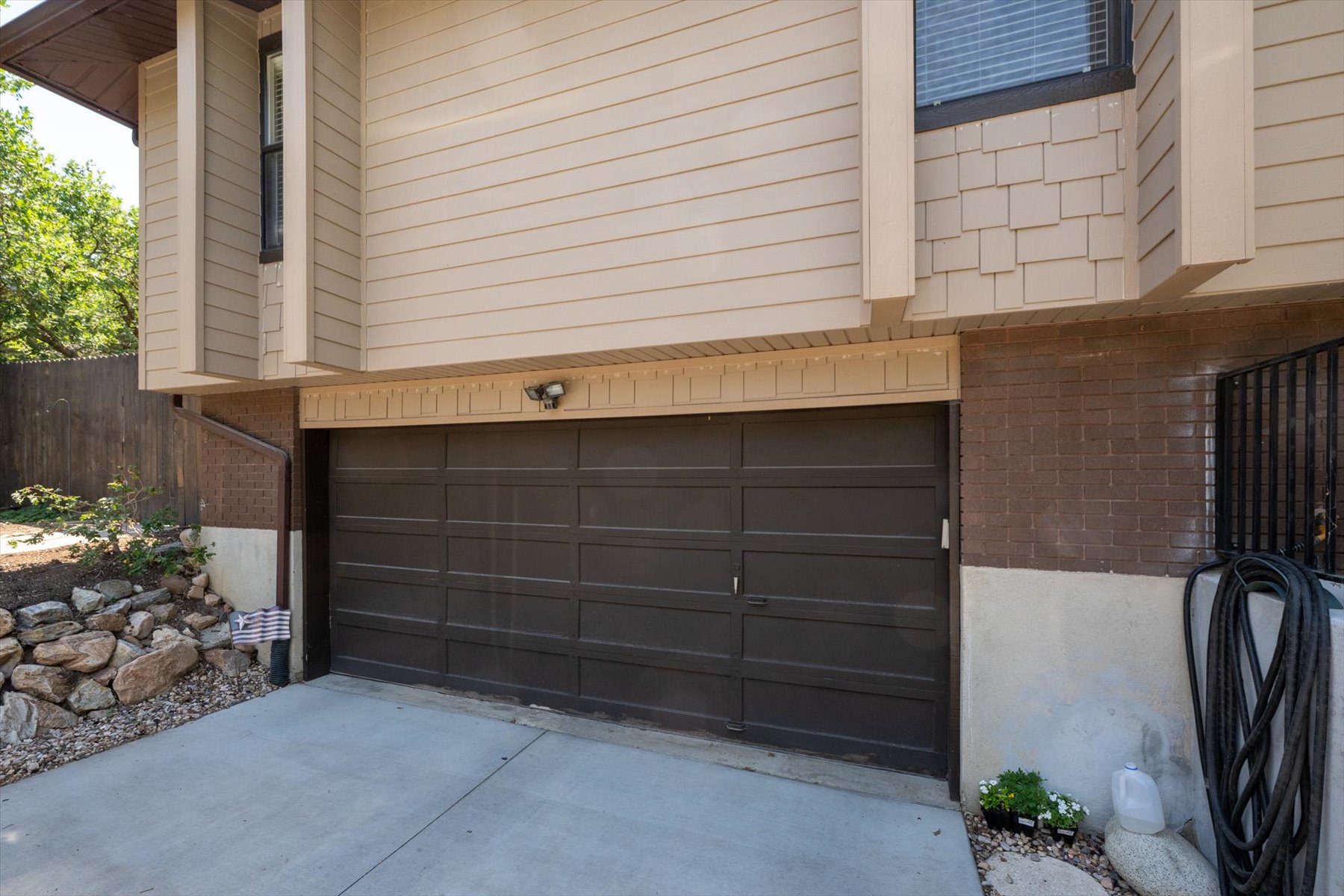 Integrated garage with a dark panel door, concrete driveway, and exterior lighting fixture