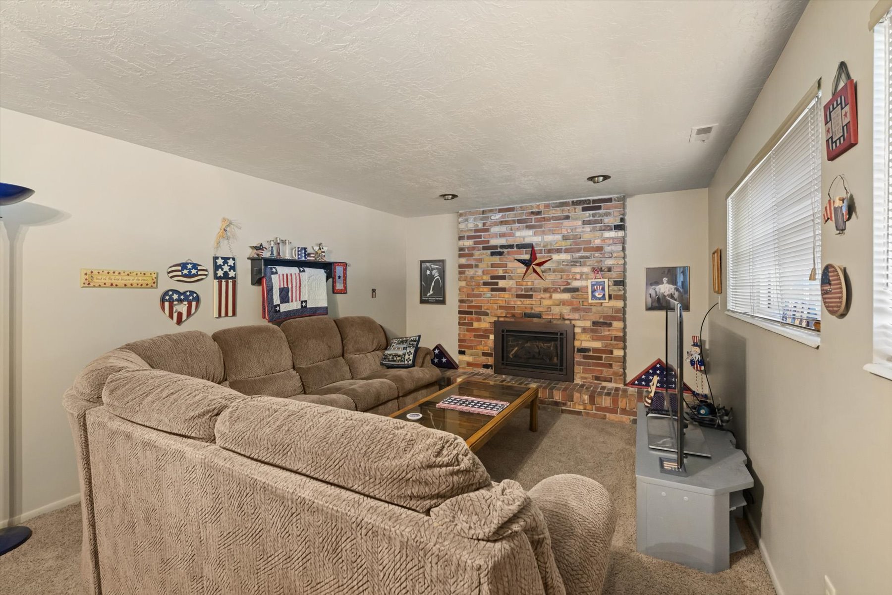 Living area featuring a brick fireplace with an insert, recessed lighting, and carpet flooring