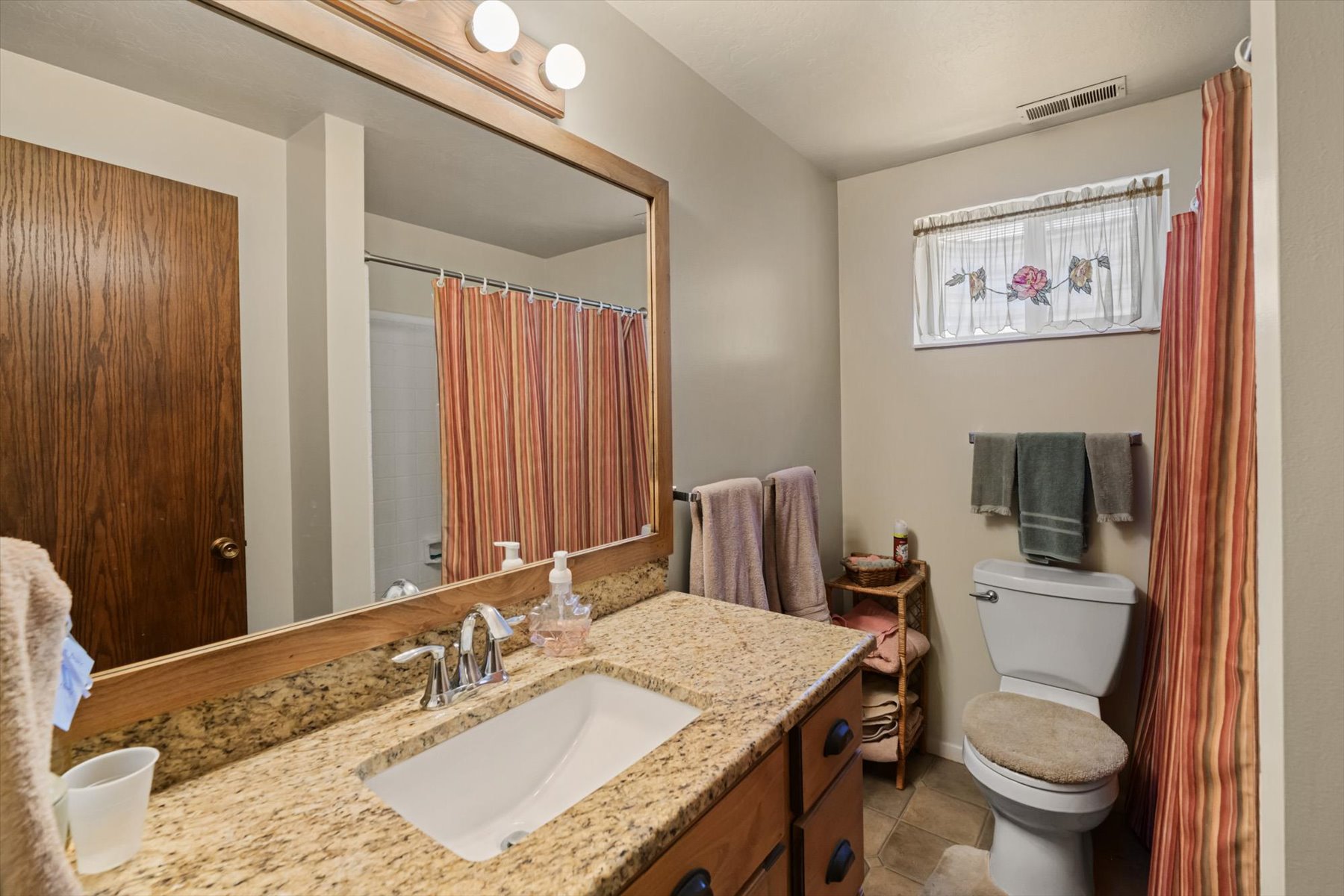 Bathroom featuring a vanity with a light-toned stone countertop, an undermount sink, and a chrome faucet