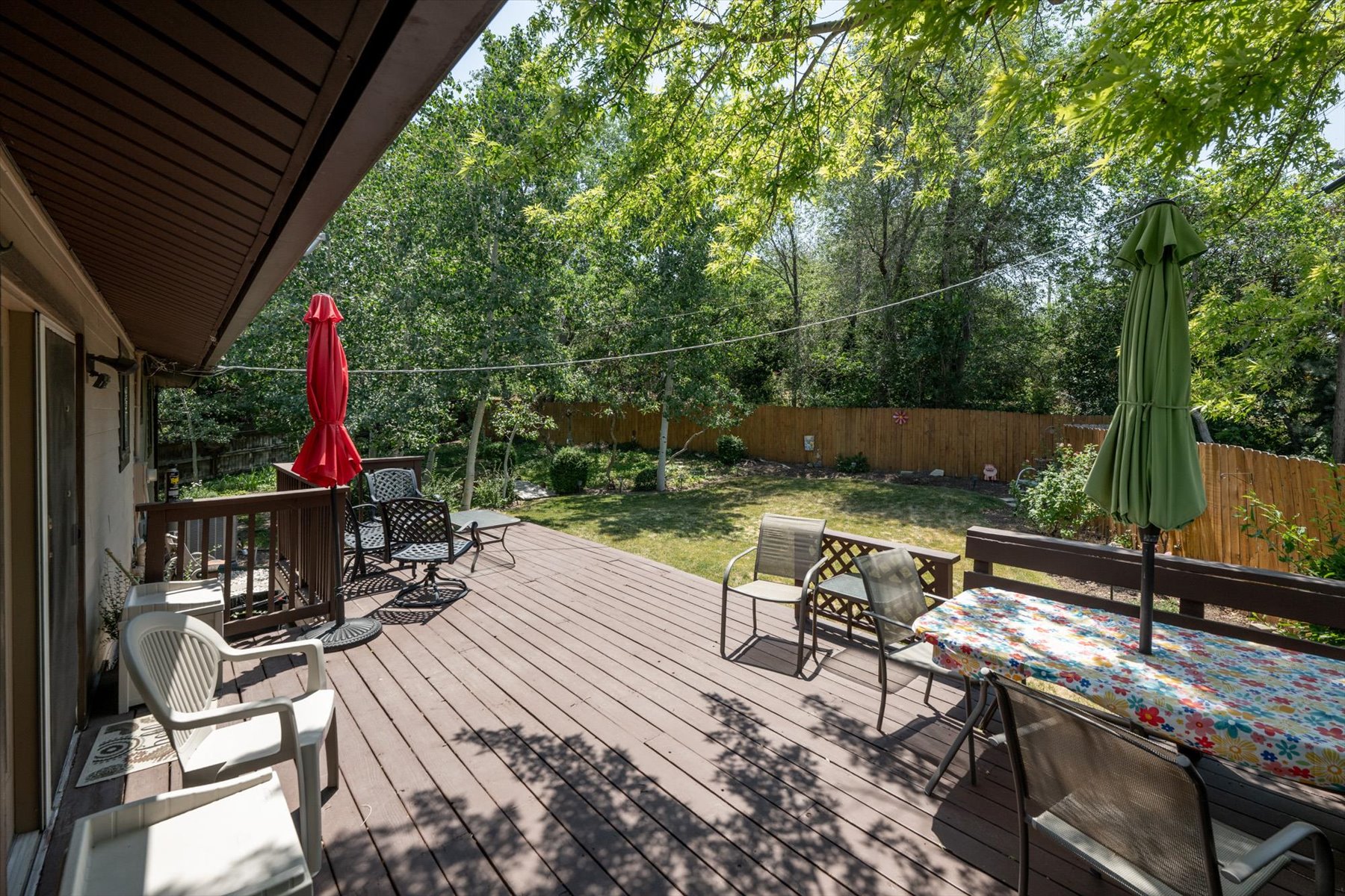 Expansive wood-finish deck with dark wood railing and a spacious green lawn