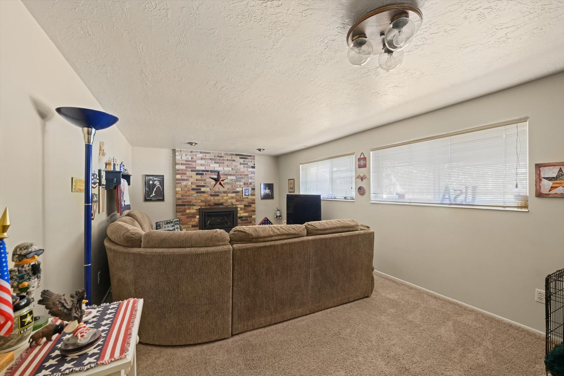 Living area featuring a brick-surround fireplace and neutral-toned carpeting