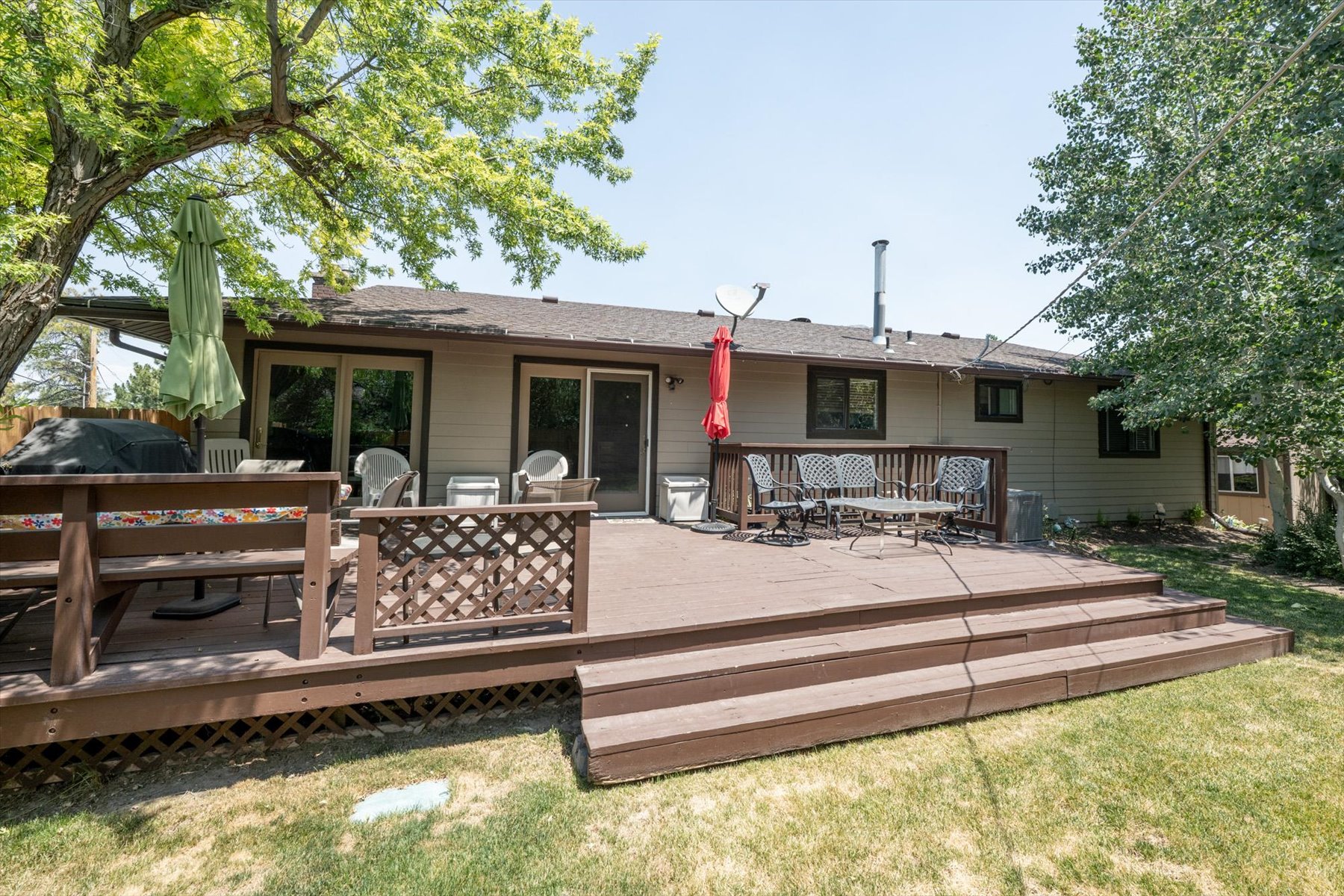 Expansive multi-level wood deck featuring lattice skirting, a wood railing with decorative diamond cutouts, and direct access to the interior via double glass sliding doors