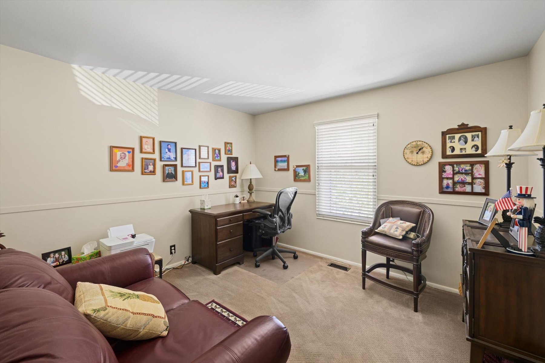 Carpeted interior room with neutral-toned walls, featuring a window with white blinds