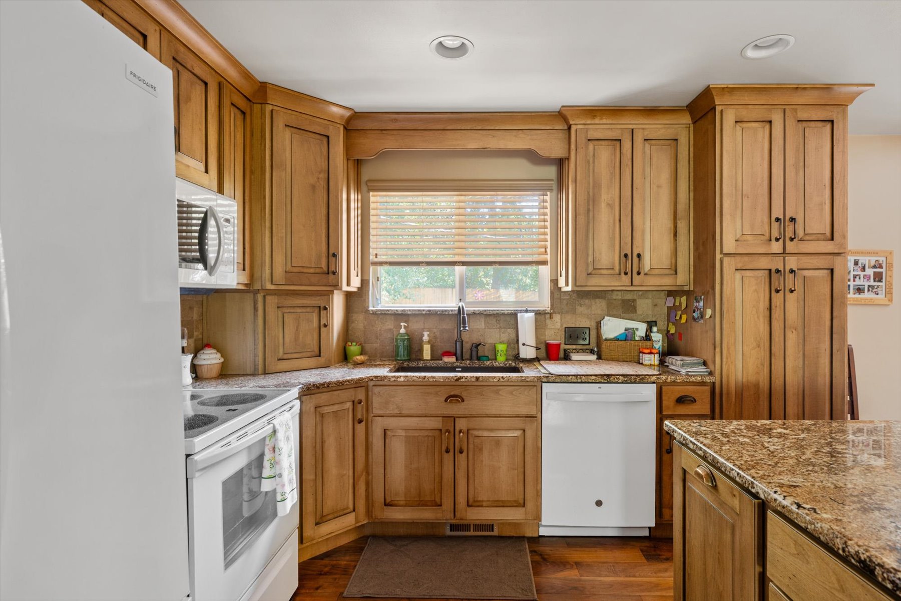 Kitchen featuring wood-finish cabinetry, stone countertops, and wood-finish flooring