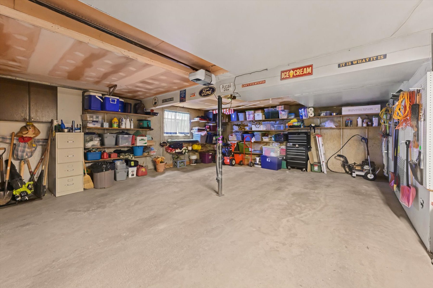 Spacious utility area featuring a concrete floor, exposed wood ceiling joists, and a window