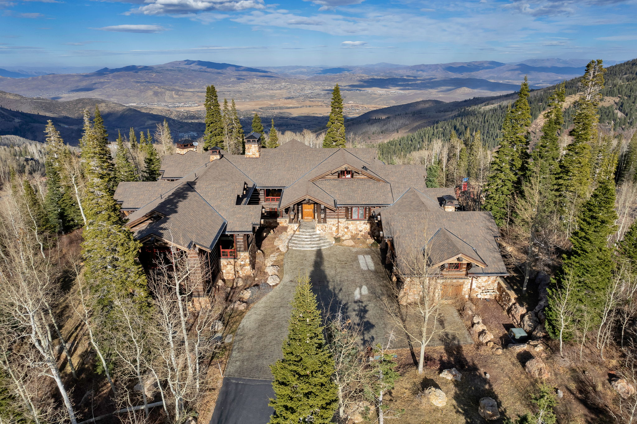 Mountain lodge-style residence featuring a multi-gabled roofline and natural stone and wood siding