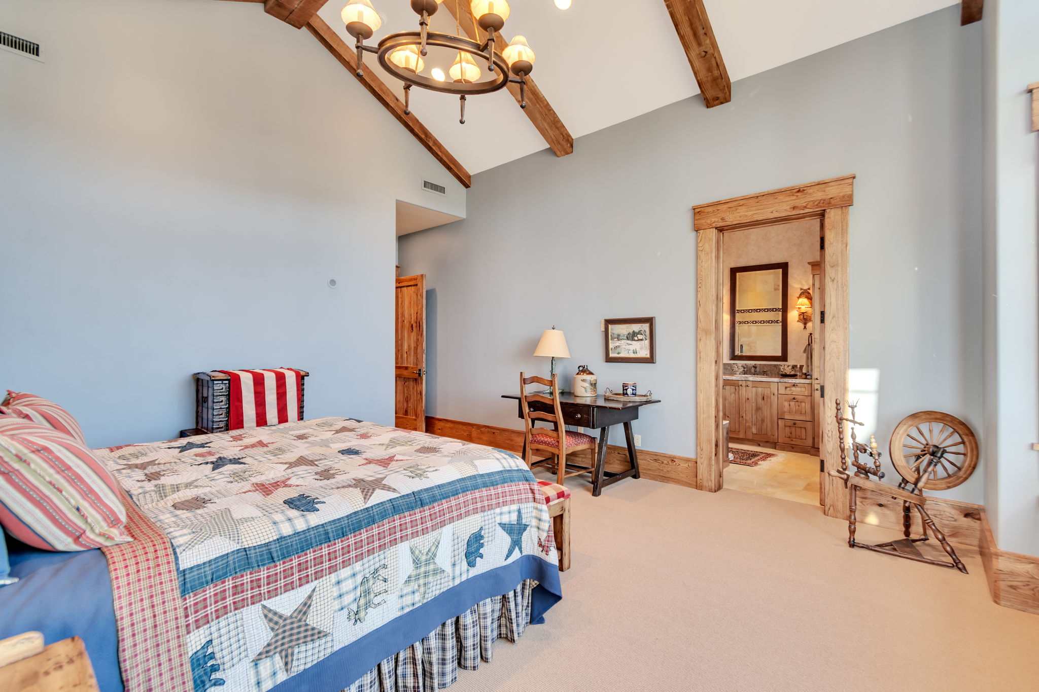 Vaulted ceiling with exposed wood beams, wood-trimmed doorway, recessed lighting, and a prominent chandelier