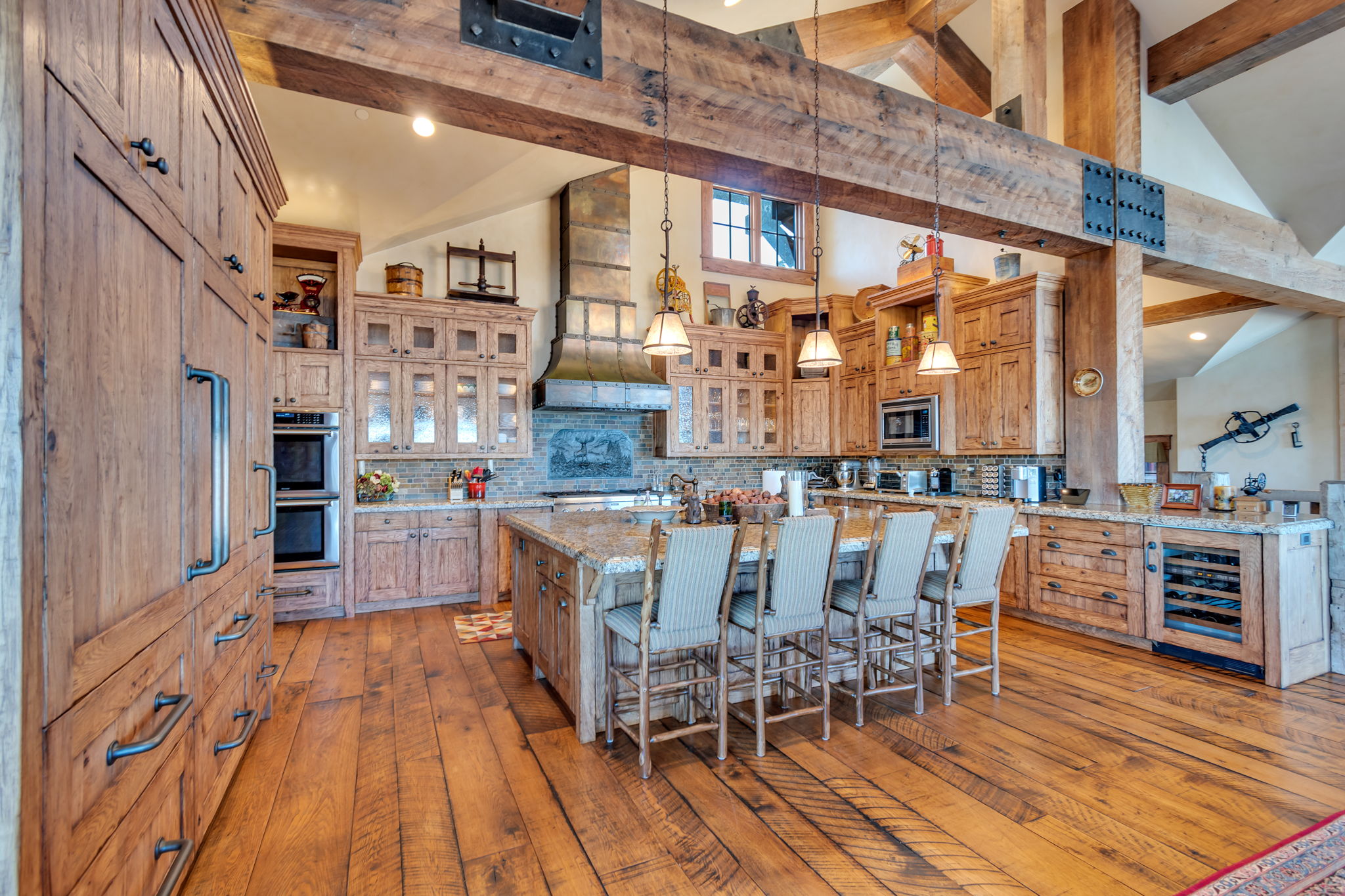 Gourmet kitchen with wood-finish flooring, exposed wood beams, and a large central island