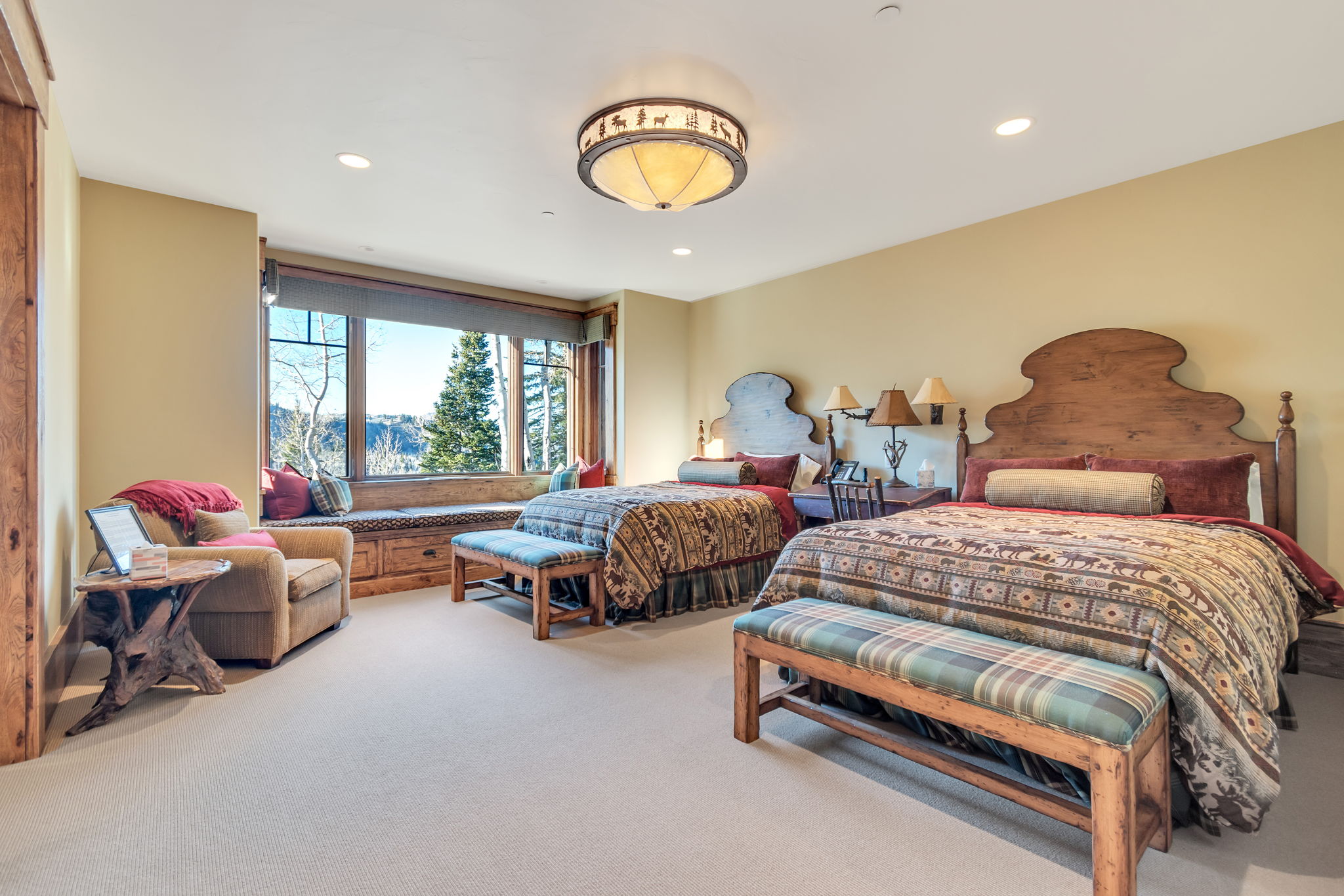 Expansive room featuring a large window with a built-in window seat and integrated storage, recessed lighting, wall-mounted light fixtures, a decorative ceiling light fixture, and light-colored carpeting