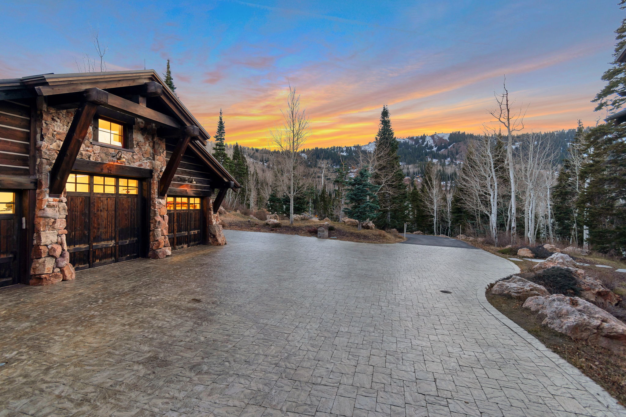 Rustic-style garage featuring stone and timber construction with wood garage doors