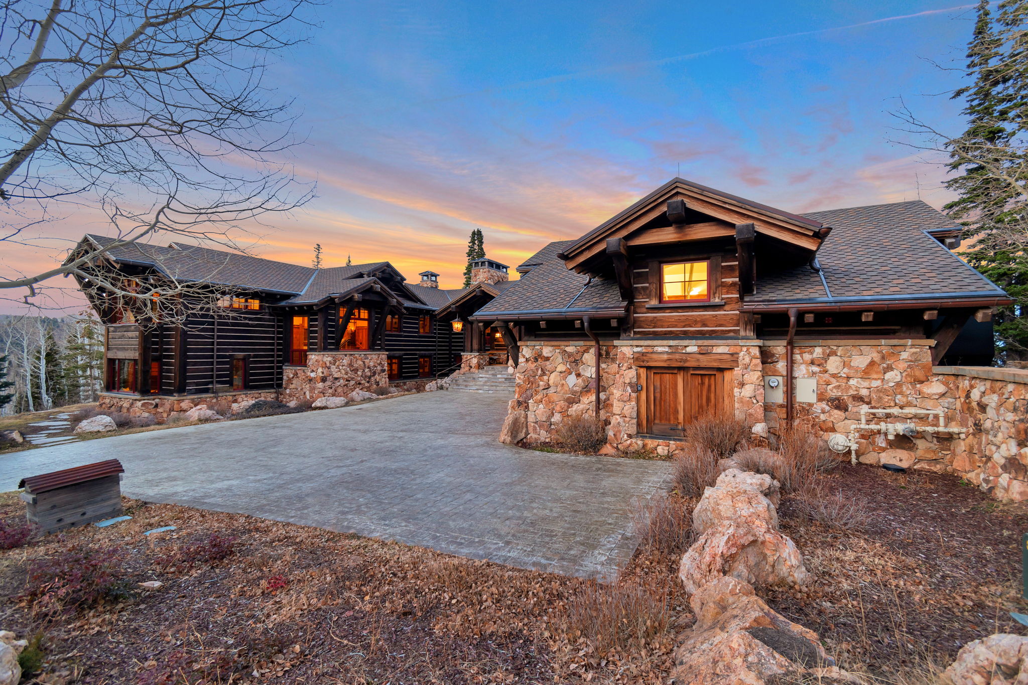 Stone and log construction exterior with a paved driveway