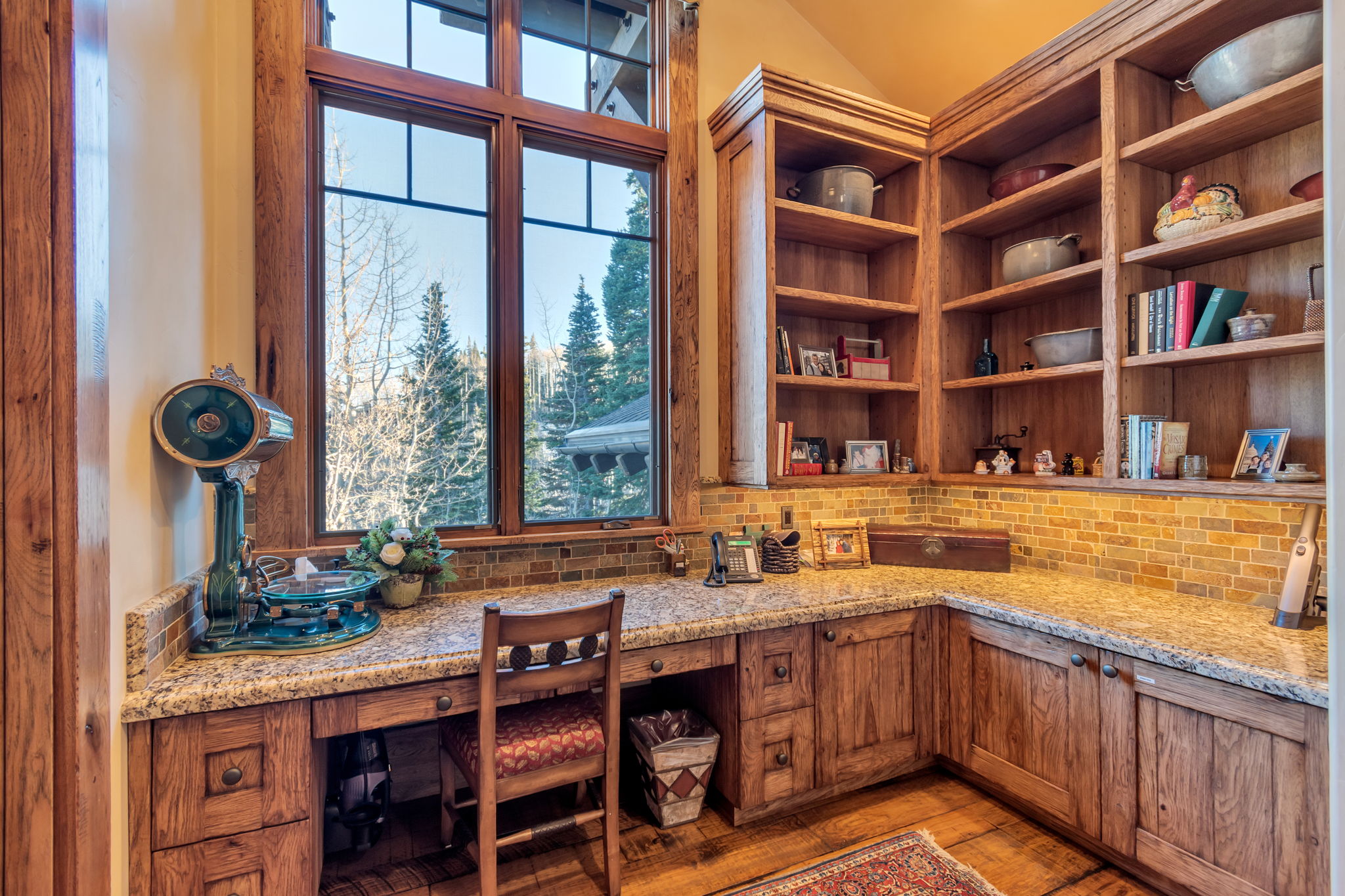 Custom-built desk area featuring wood-finish cabinetry, granite countertops, and a mosaic tile backsplash