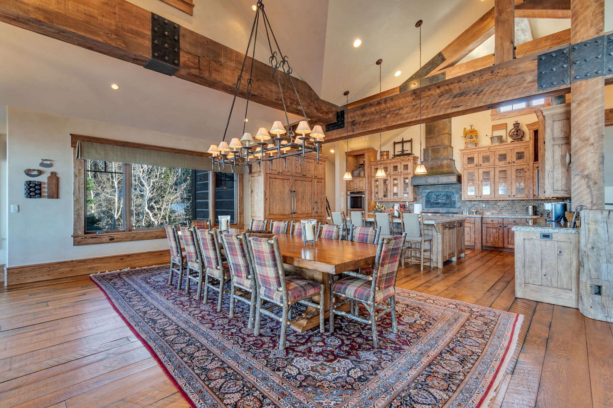 Vaulted ceilings with exposed timber beams define this expansive open-concept dining area and kitchen