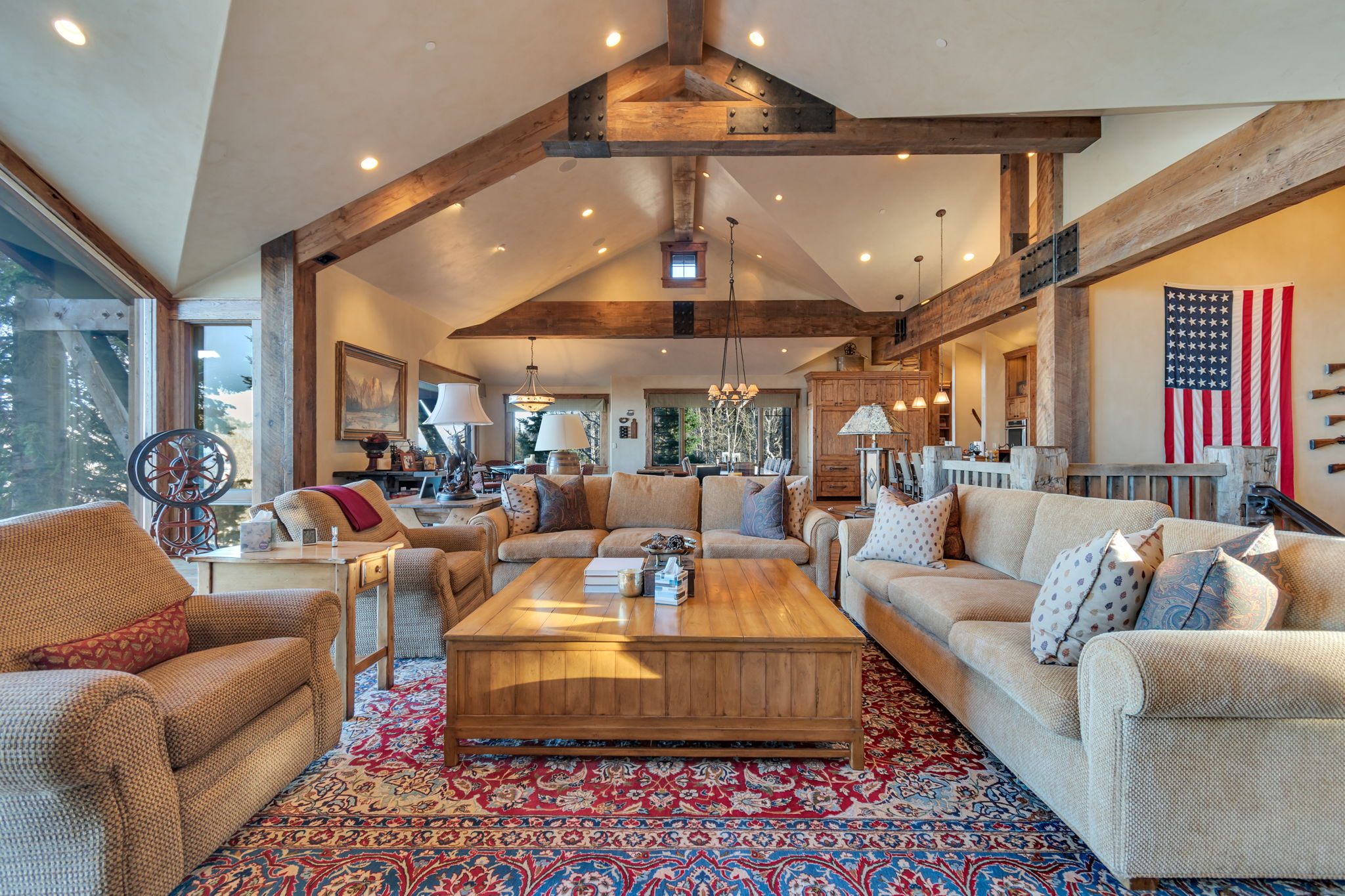 Spacious living area featuring exposed wood beams, vaulted ceilings, expansive windows, recessed lighting, and a built-in wooden coffee table