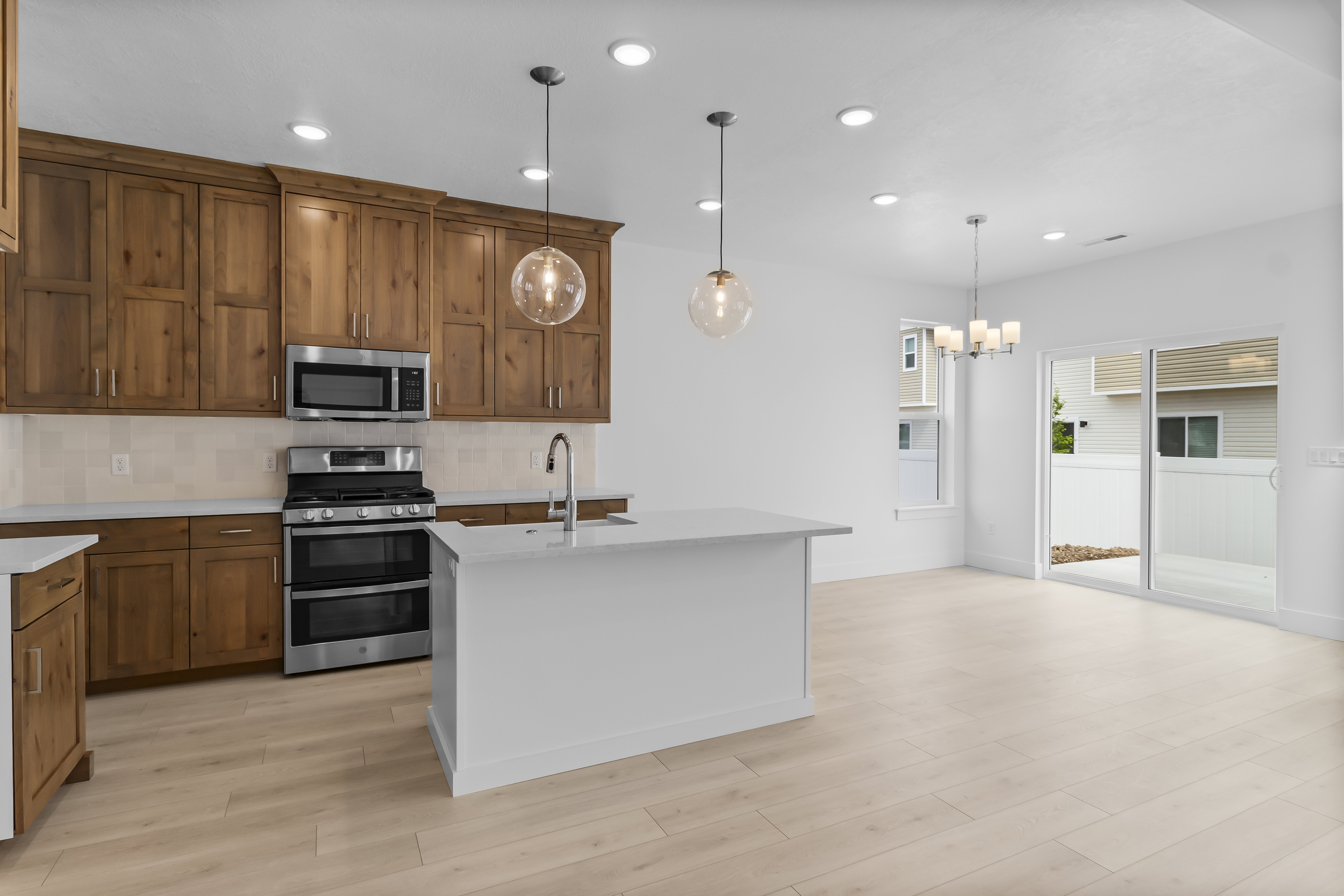 Open-concept kitchen featuring wood cabinetry, stainless steel appliances, and an island with a sink