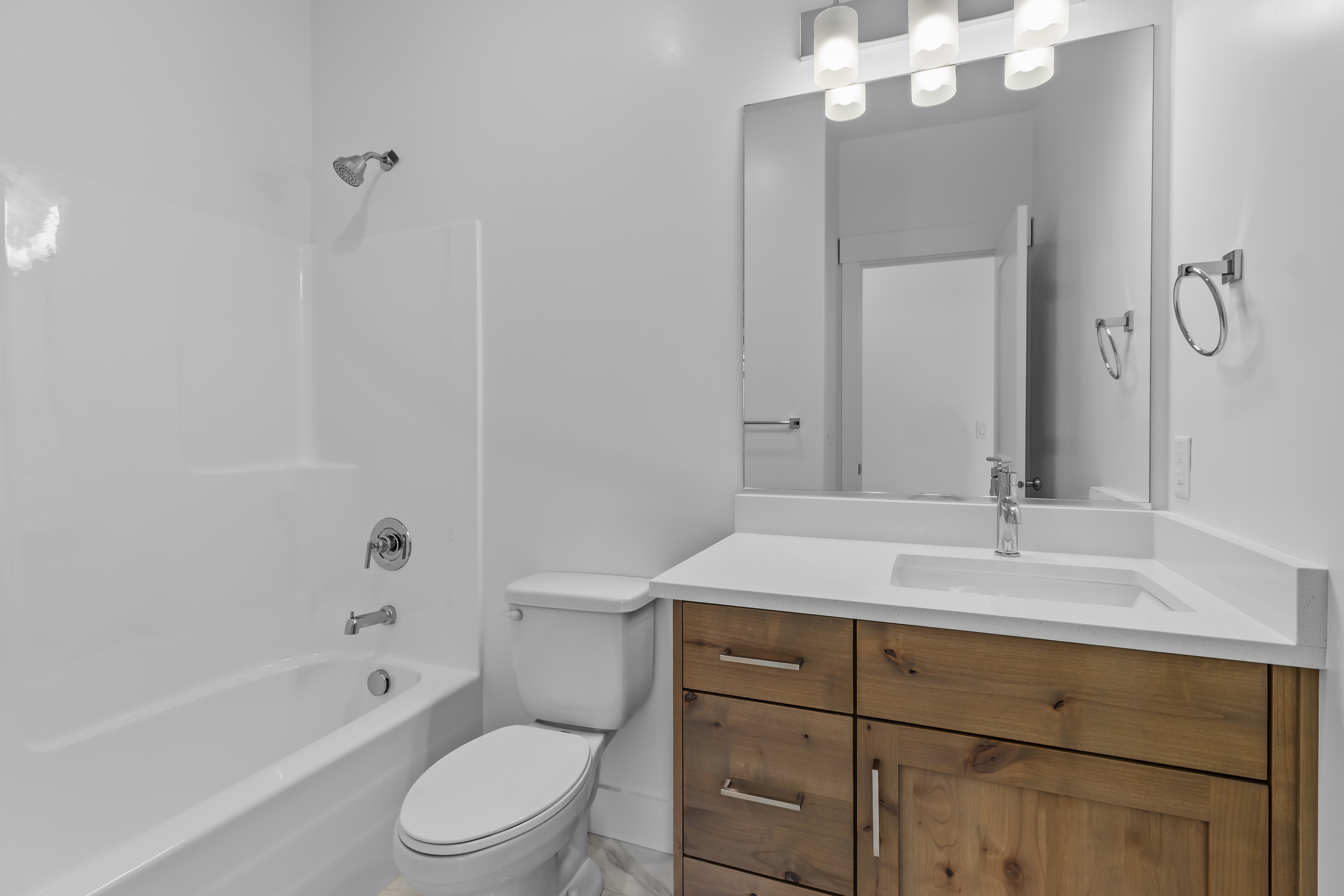 Modern bathroom featuring a wood-finish vanity with ample storage, integrated sink, and white countertop